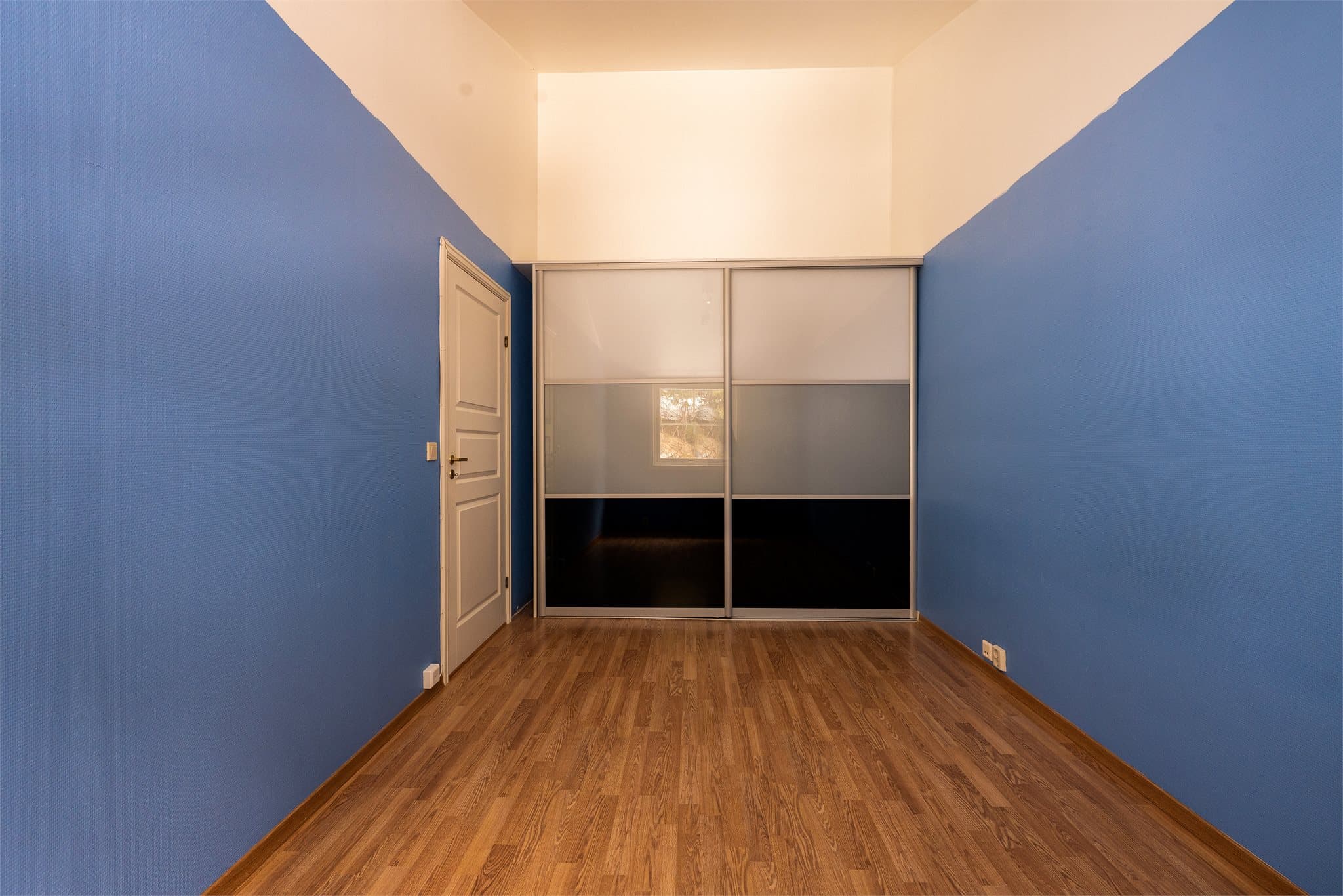 Rommet er innredet med en romslig skyvedørsgarderobe.