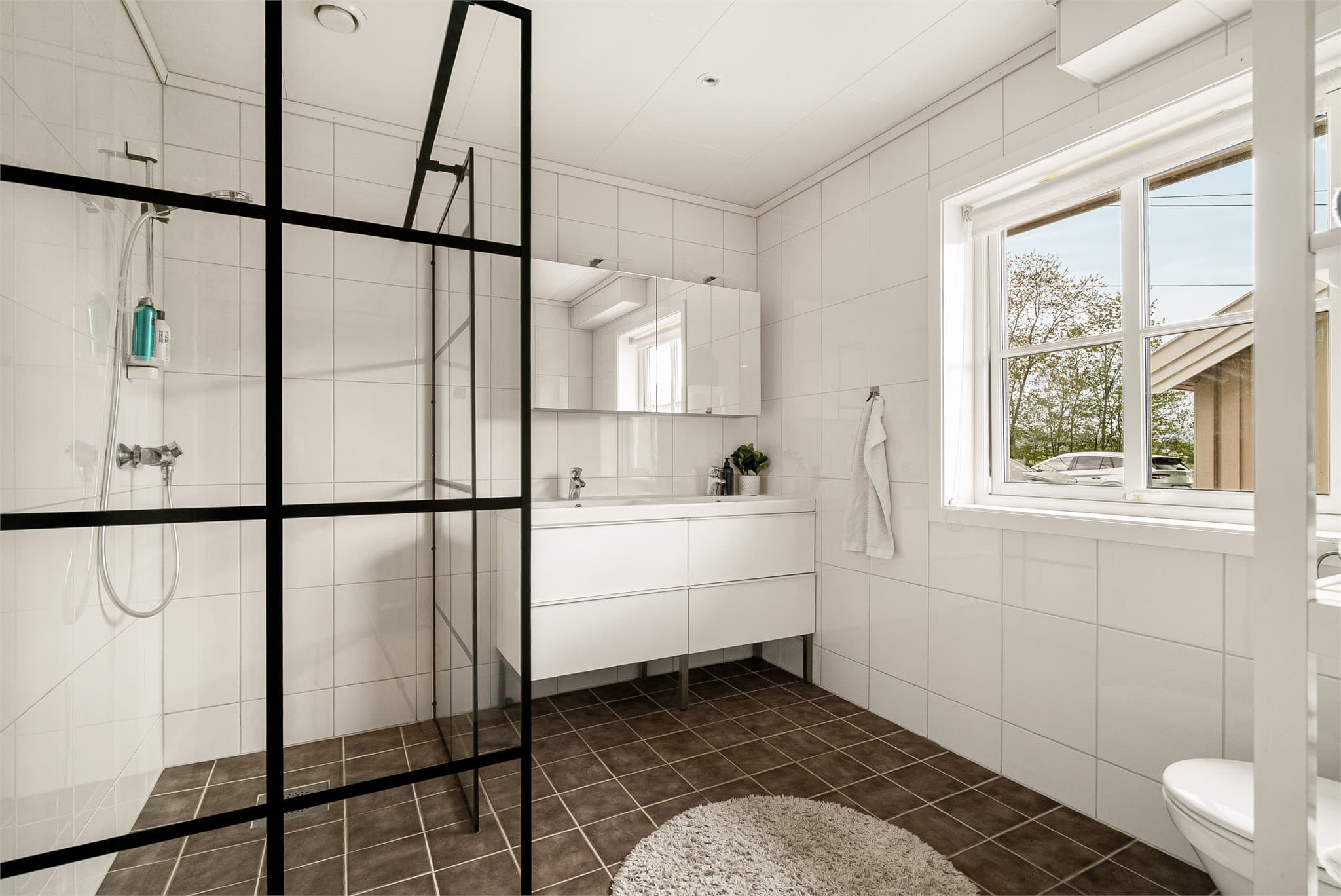 Lyst, flislagt baderom med moderne dobbel servantinnredning, romslig dusjhjørne og toalett, samt downlights i himlingen.