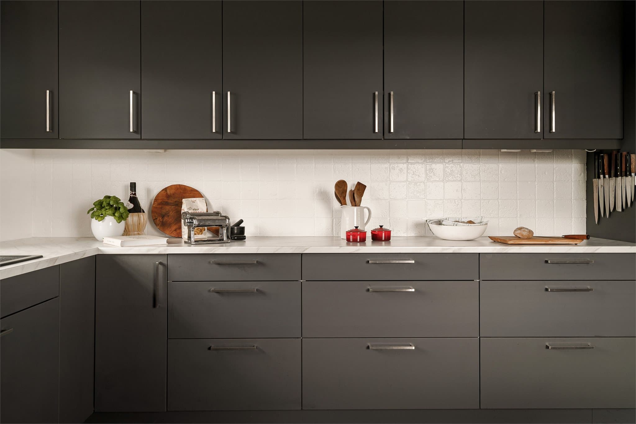 Moderne og stilrent kjøkken med glatte fronter og integrerte hvitevarer fra Siemens og Aeg som oppvaskmaskin, koketopp, kaffemaskin og stekeovn.
