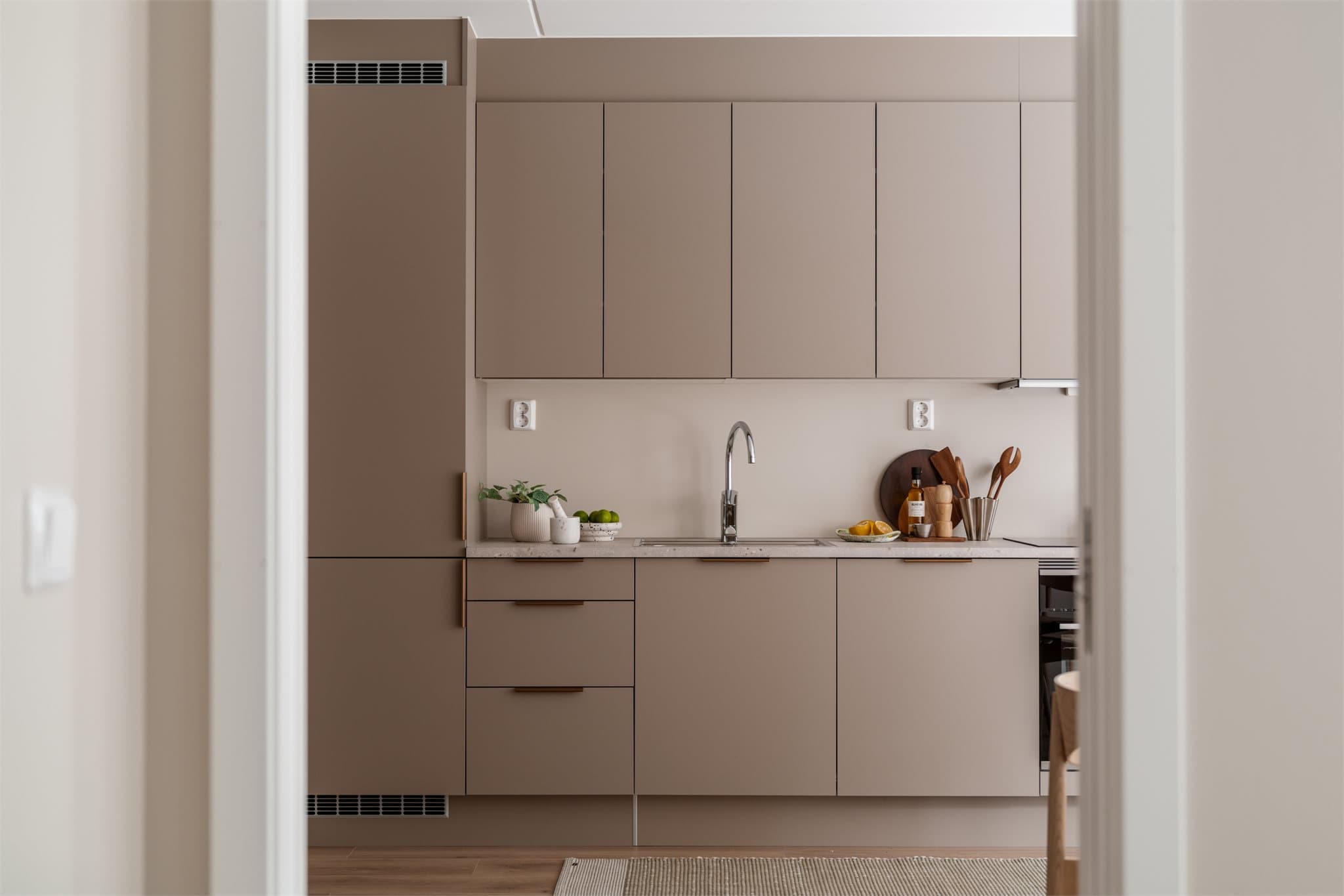 Moderne kjøkken med elegant, lys innredning som gir en åpen og innbydende atmosfære.