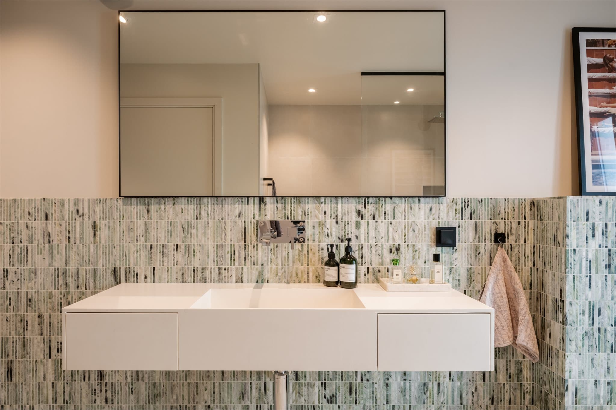 Gulvet har behagelige varmekabler, og rommet er innredet med vegghengt toalett med innebygget sisterne, stilren baderomsinnredning med slette fronter og Copenhagen bath vask i kompisitt, samt en romslig dusjsone med glassvegg.