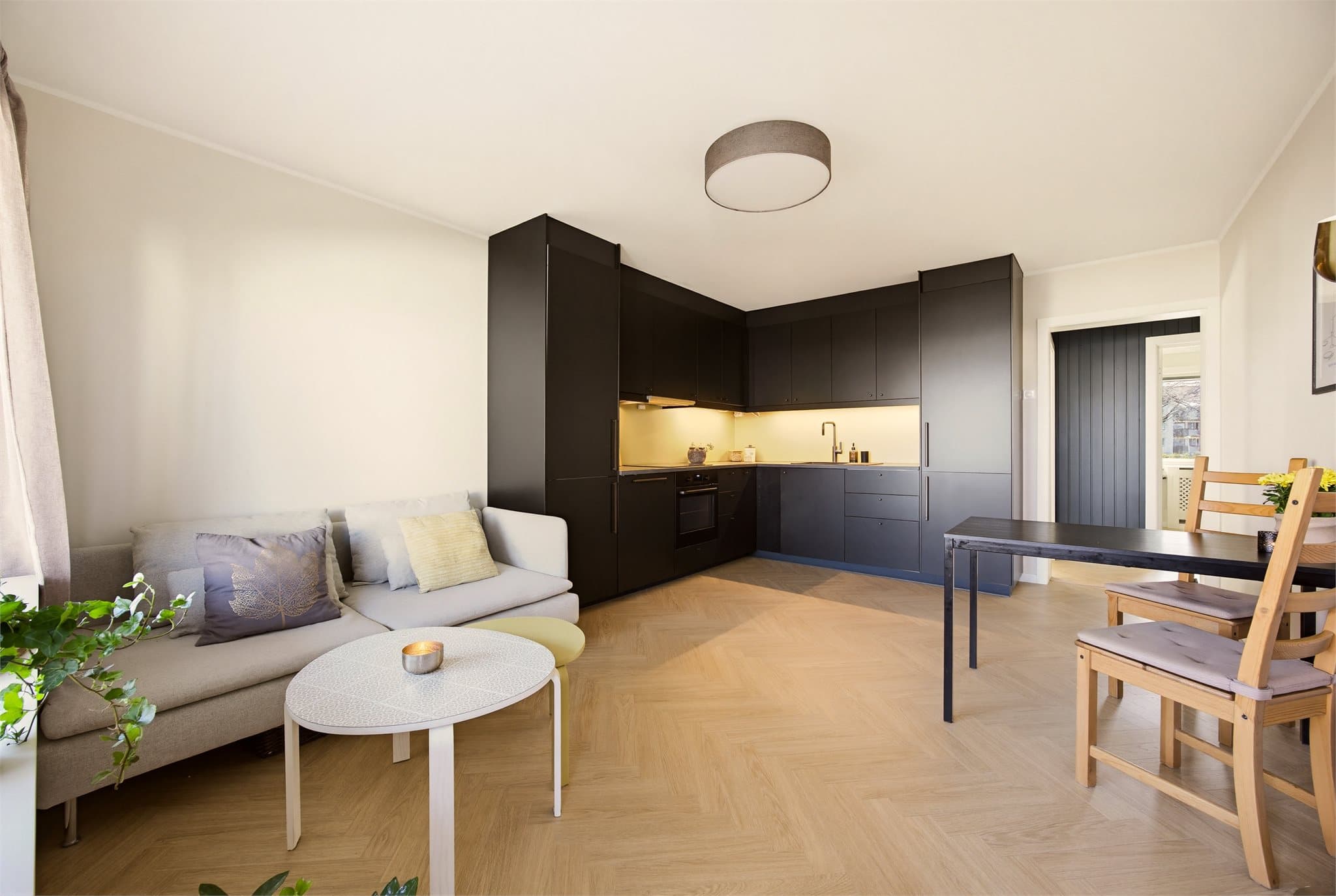 Hovedsonen byr på en stor og åpen stue- og kjøkkenløsning med moderne fargevalg og stilfullt gulv.
