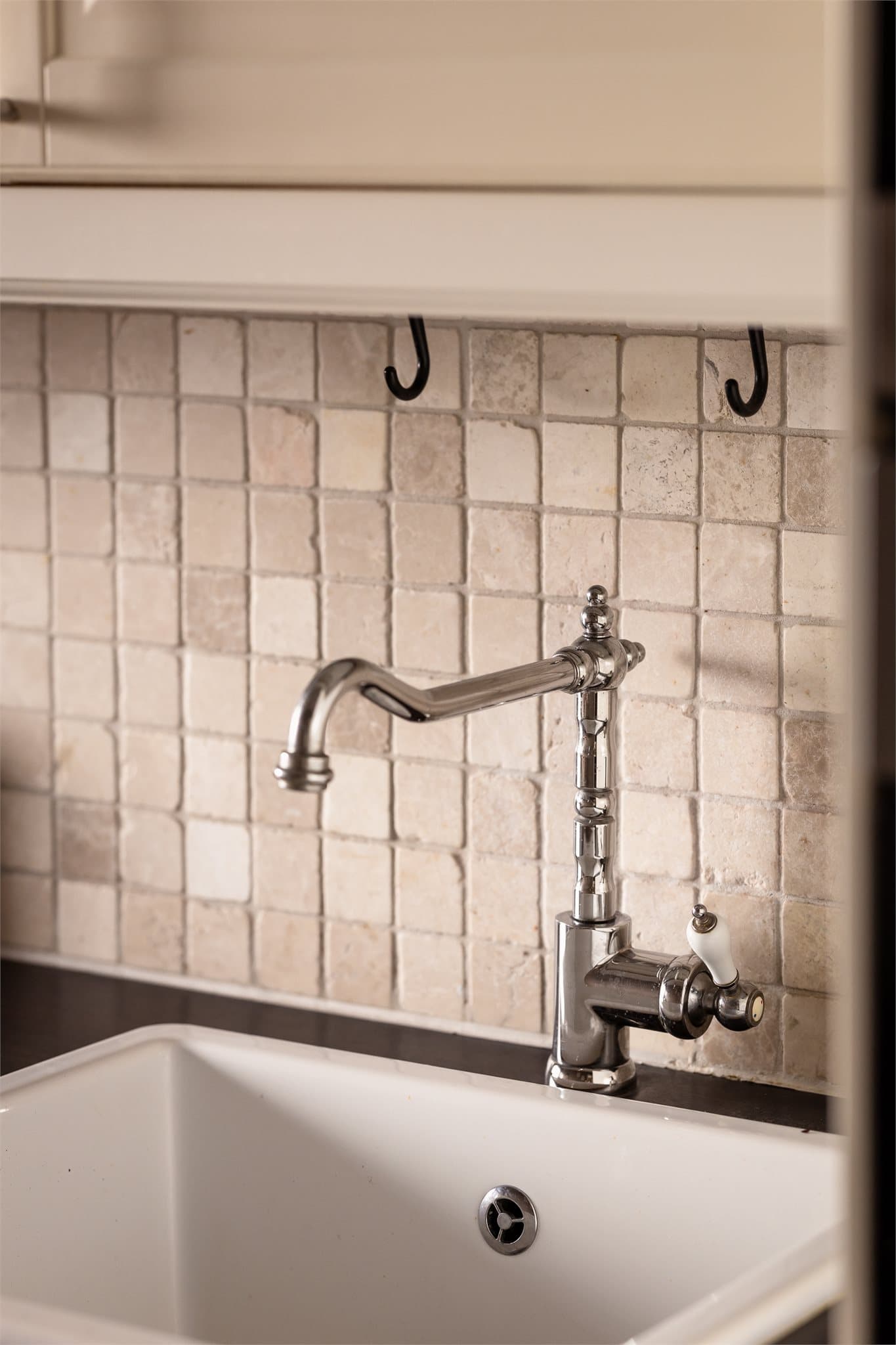 En flott vask og lekkert blandebatteri samt delikate fliser mellom benk og skap.