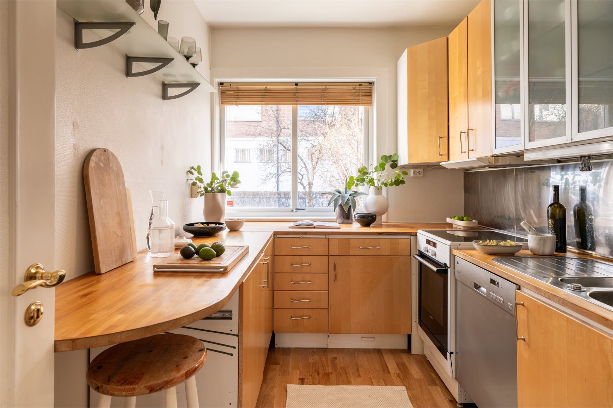 Kjøkkeninnredningen har gjennomgående fronter i tre som gir et varmt og tidløst uttrykk, hvor enkelte overskap er utstyrt med glassfelt. Benkeplaten i heltre gir en solid og innbydende arbeidsflate.