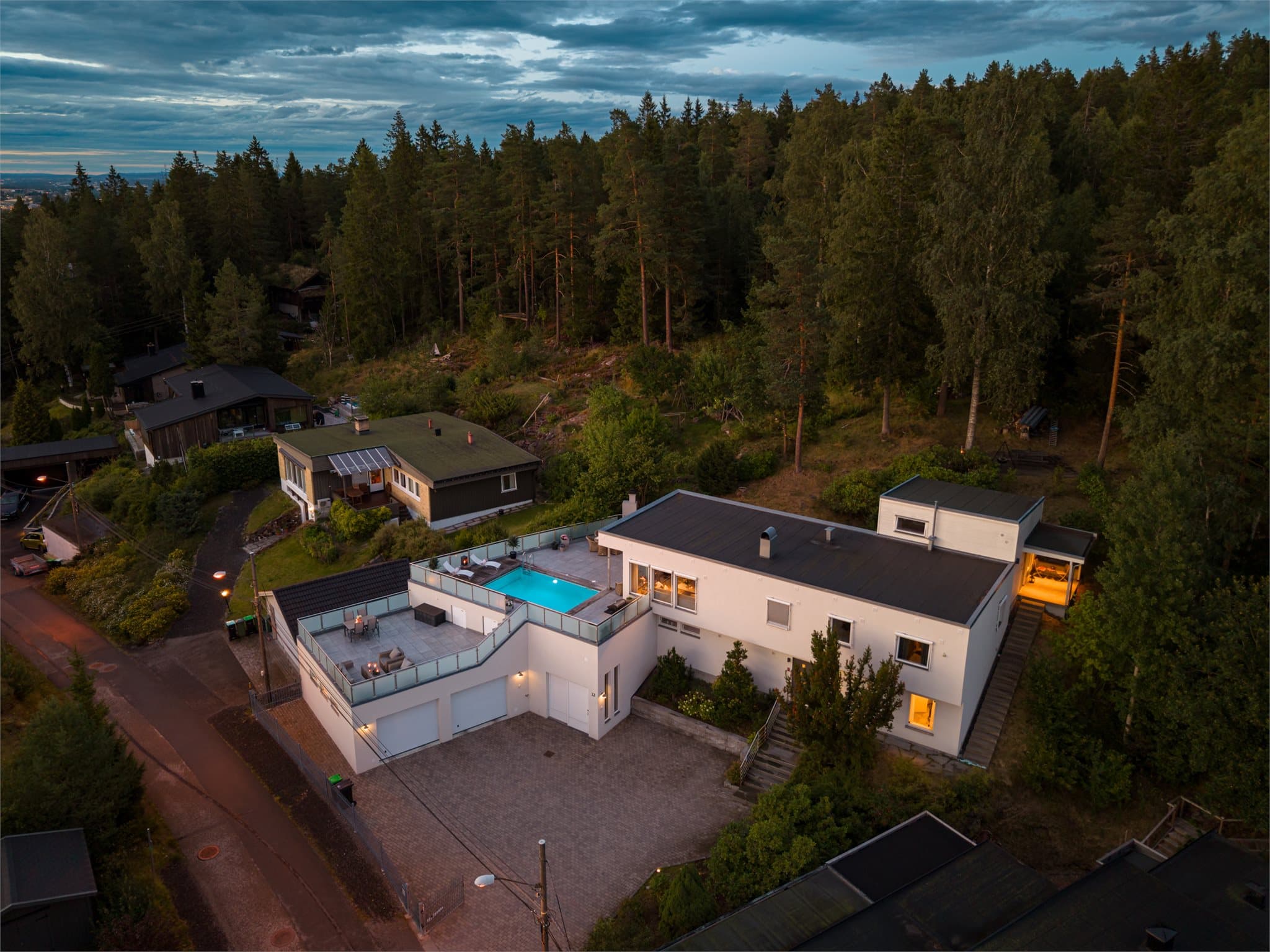 Den store natursteinsterrassen er selve hjertet i uteområdet – her er det satt av plass til både grillkos og lange sommerkvelder rundt bordet, med tripod-grill klar til bruk og utsikt utover Romerike i bakgrunnen.
