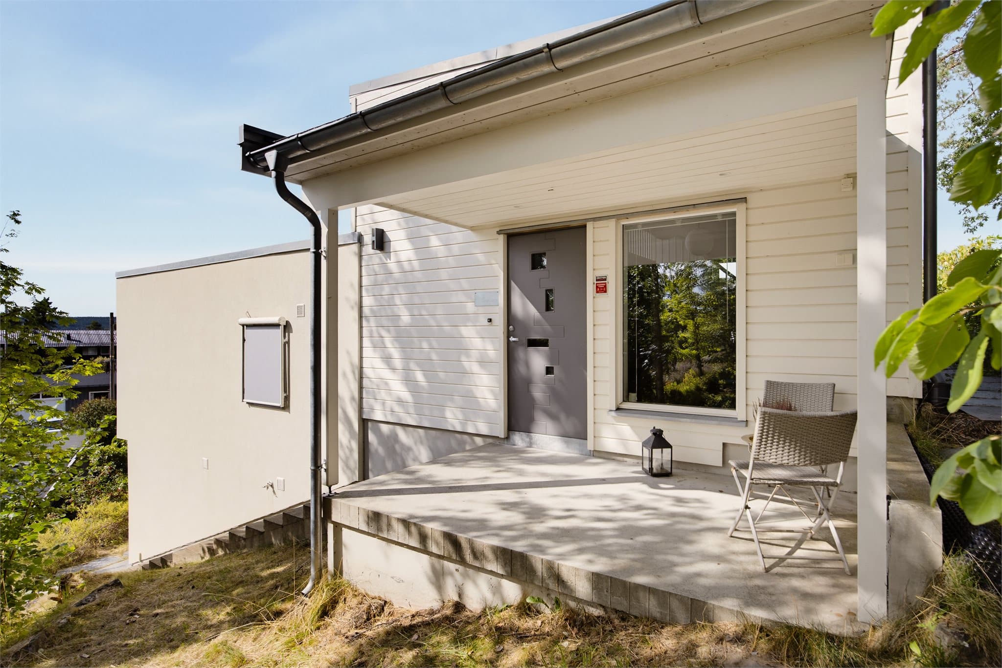 Overbygd inngangsparti med plass til sittegruppe.