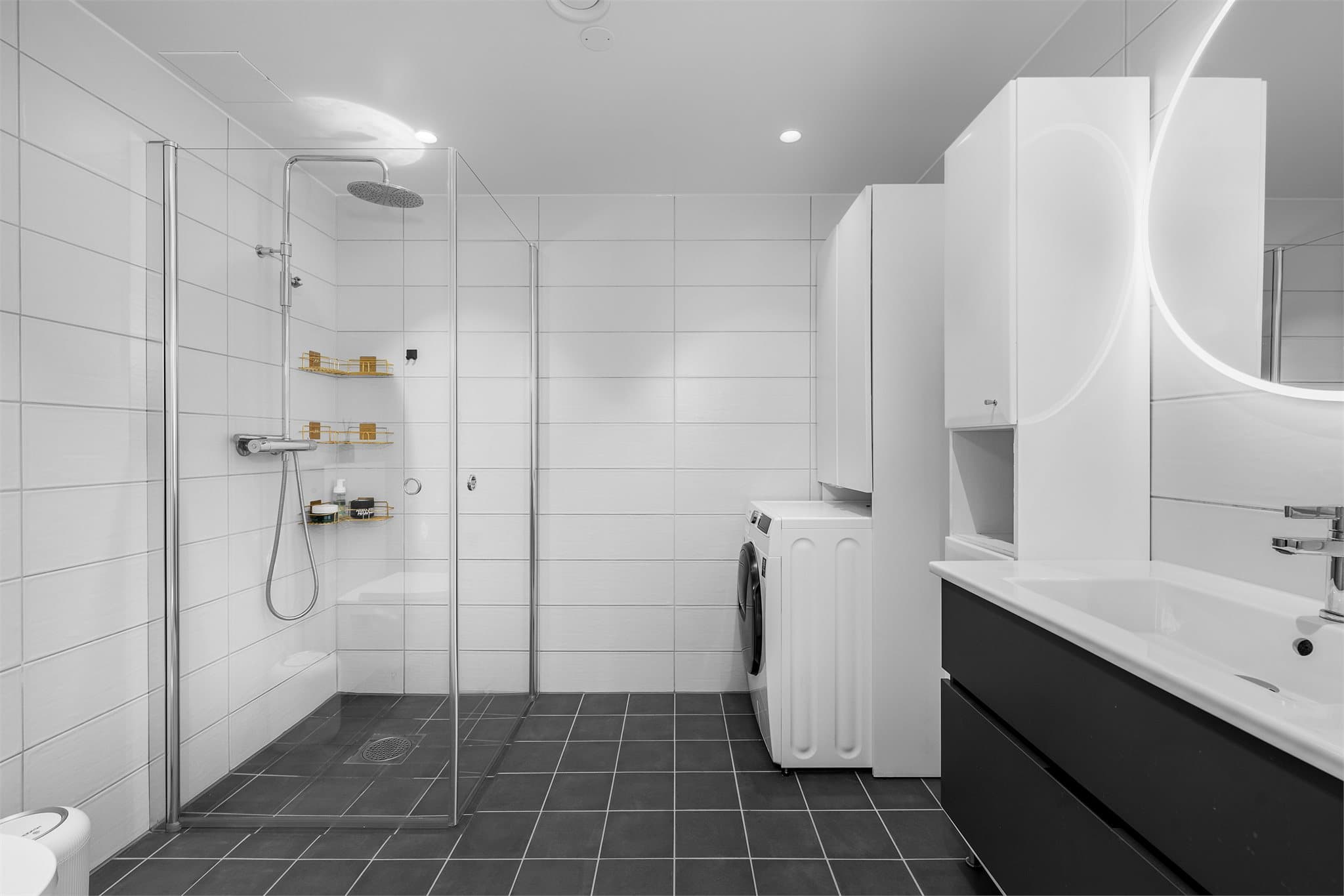 Delikat flislagt bad med mørke 20x20 fliser på gulv og hvite 20x60 fliser på veggene.