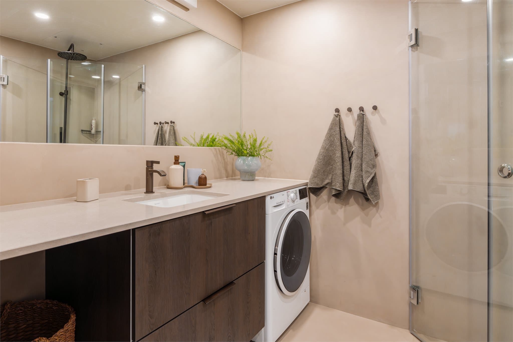 Innredningen inkluderer en bred servant med møbel under og opplegg for vaskemaskin.