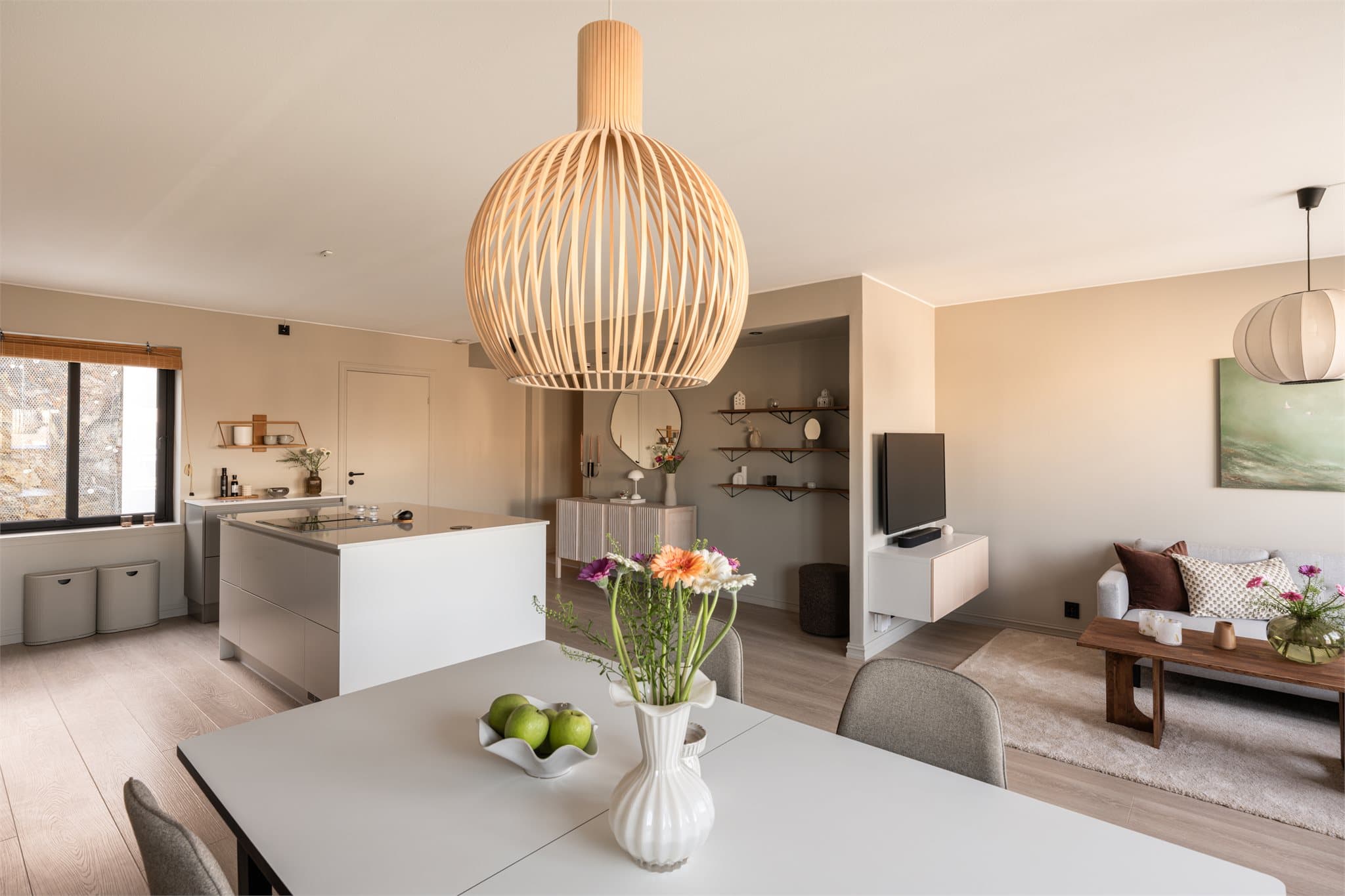 Gjennomgående eikelaminat på gulvene binder sammen stue og kjøkken på en helhetlig måte.