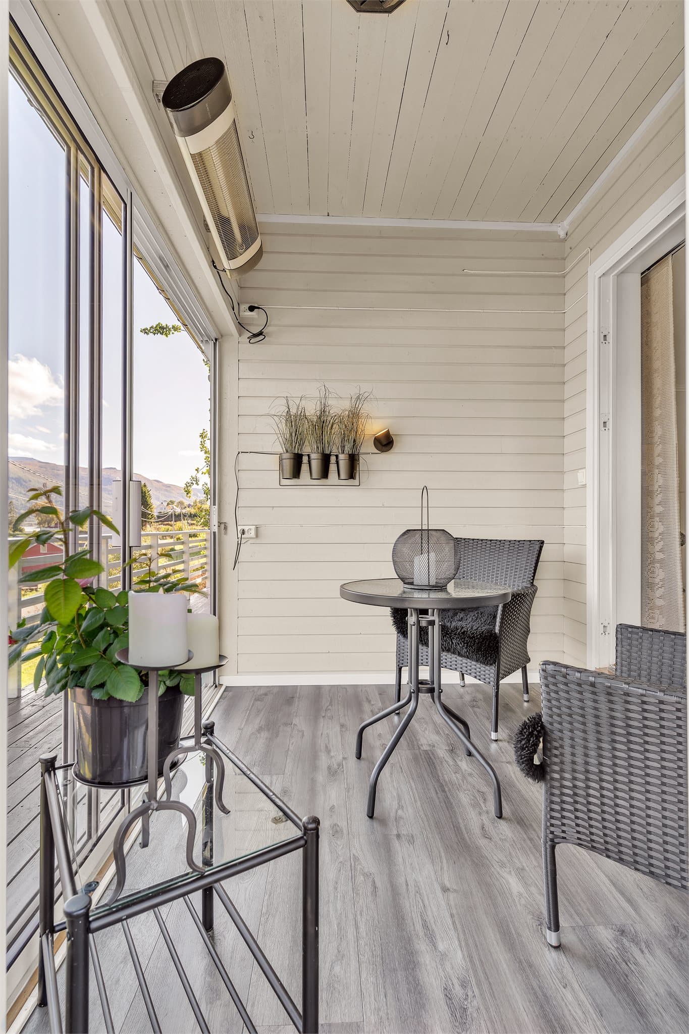 Rommet er innredet med sitteplass, veggmontert stråleovn og skyvedører i glass.