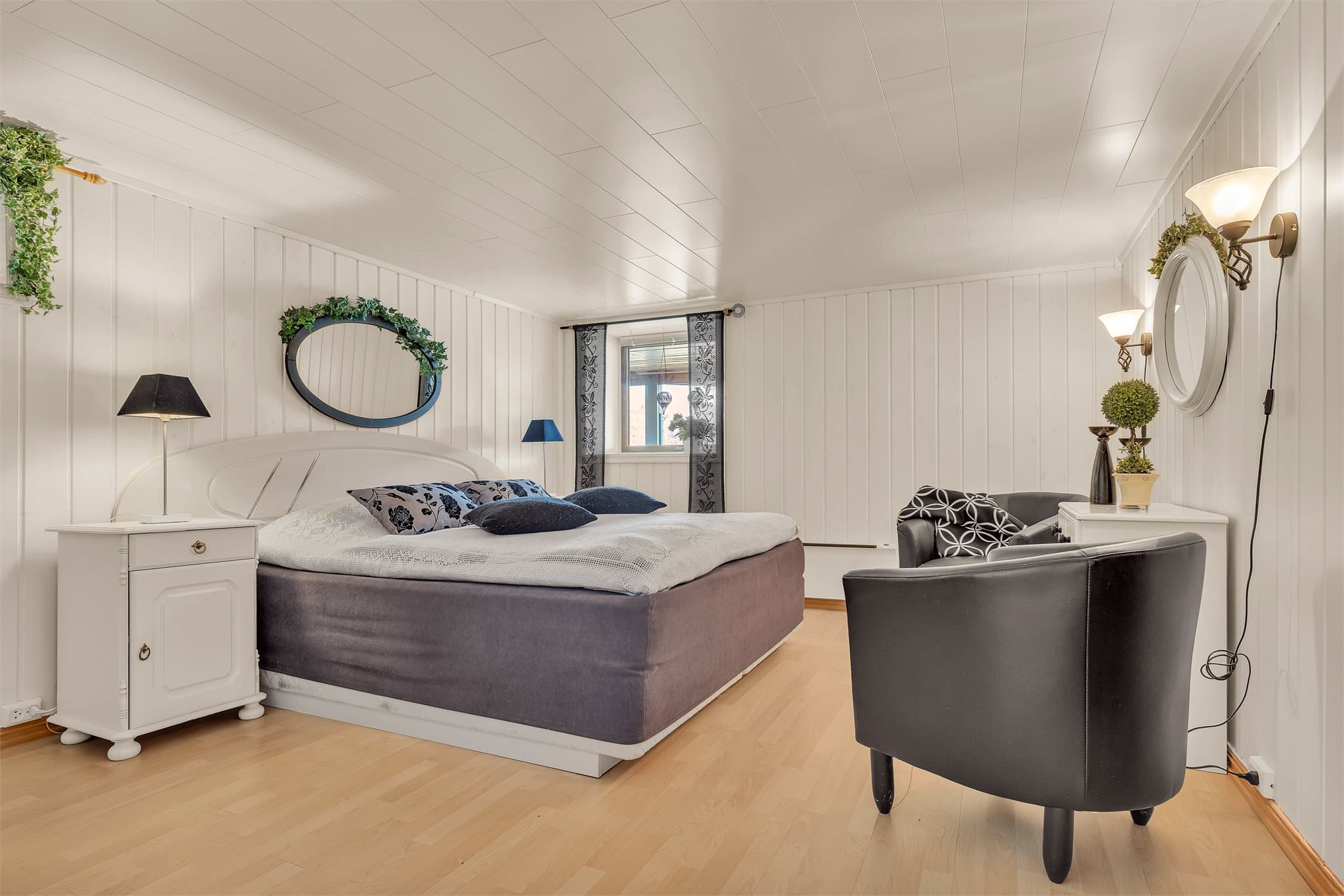 Innredet soverom i kjelleren med malt trepanel og god plass til dobbeltseng.