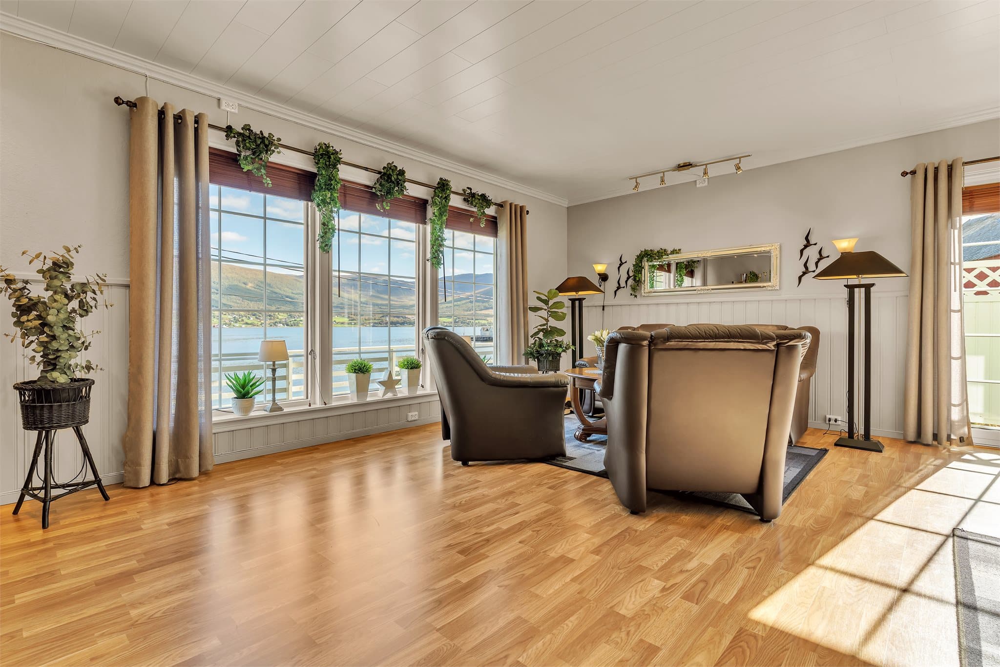 Vinduene i stuen vender mot sjøen og rammer inn utsikten mot fjordlandskapet.