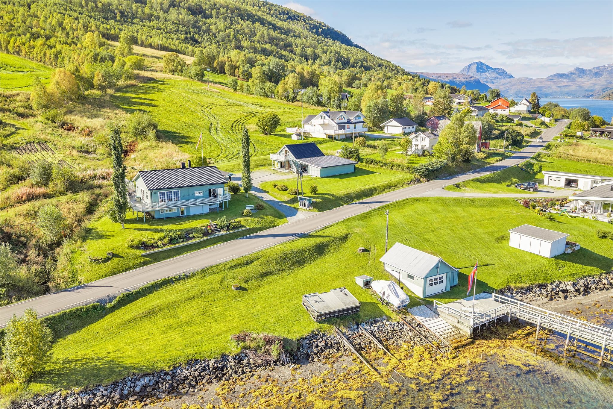 Eiendommen ligger i landlige omgivelser med åpent fjordlandskap og fjell i bakgrunnen.