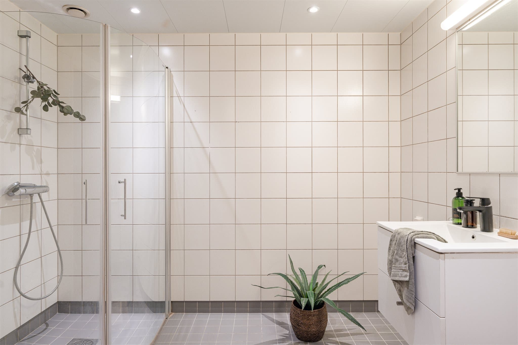 Badet er helfliset med mørke gulvfliser og hvite veggfliser.