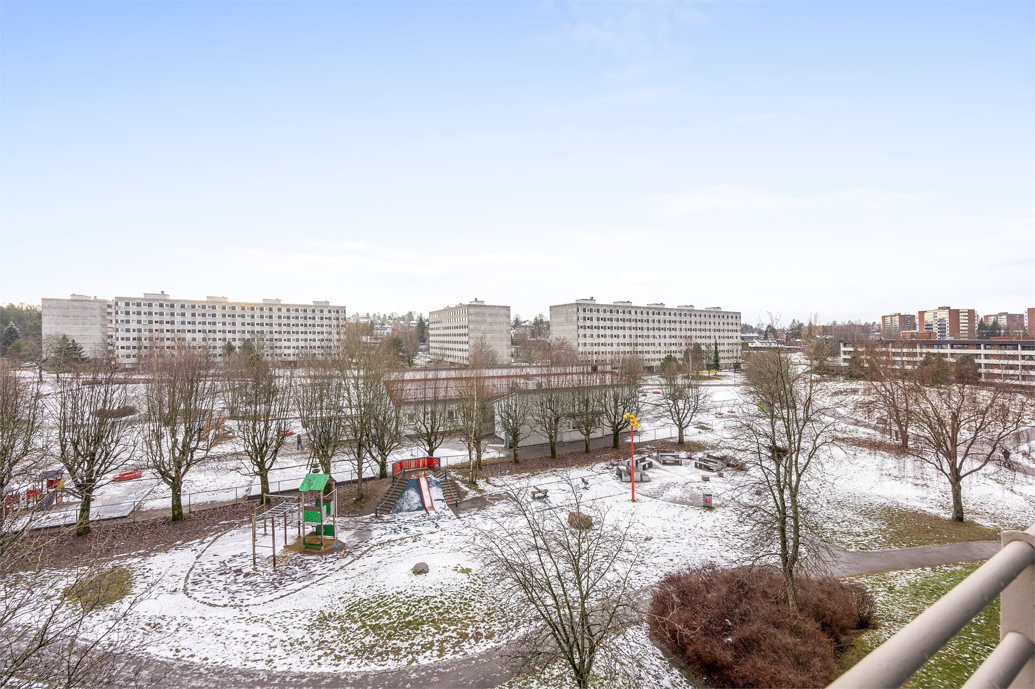 Utsikt fra balkongen utover borettslagets fellesarealer med lekeplasser og grøntområder.