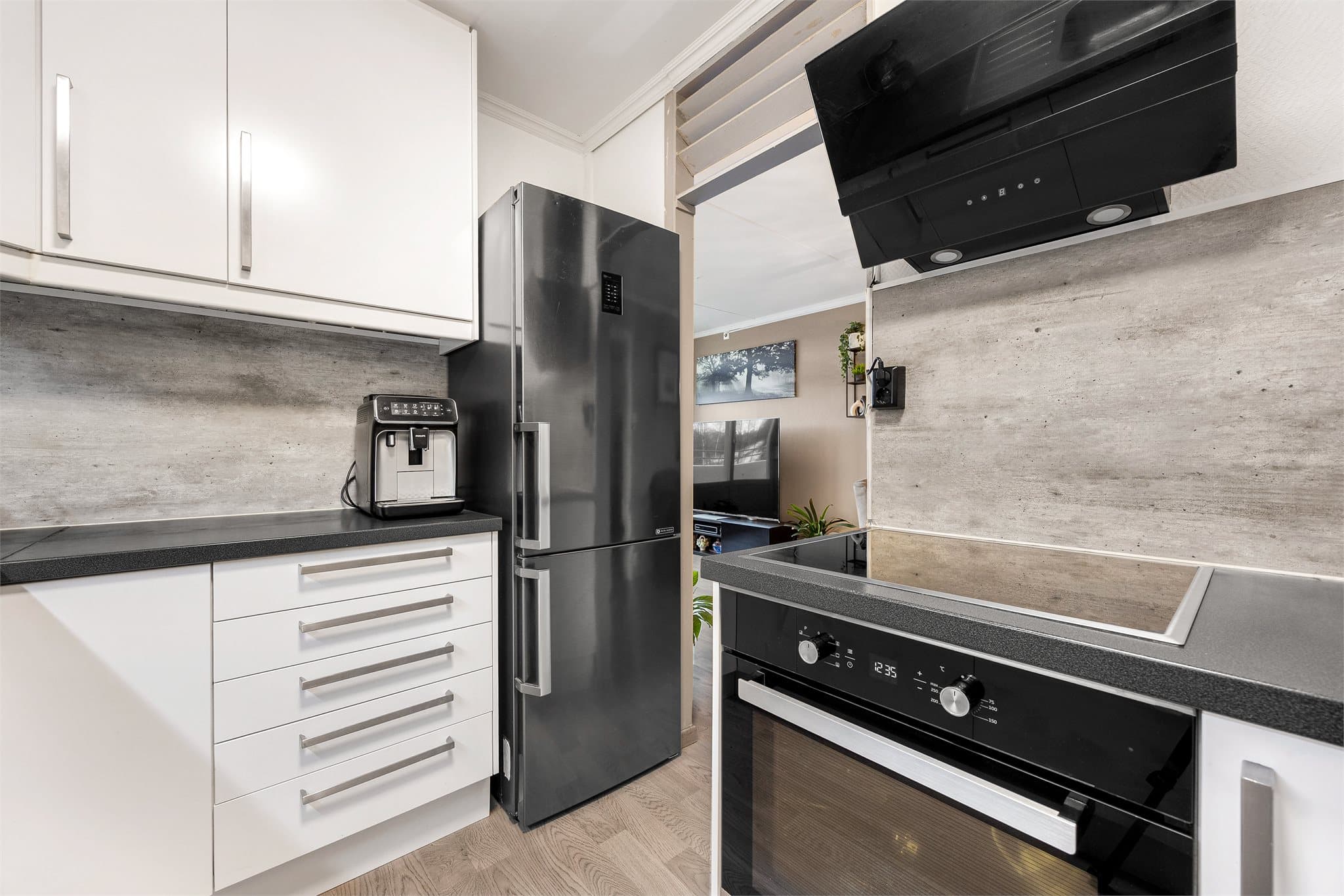 Kjøkkenet er godt utnyttet, med benkeplater og skap som strekker seg helt opp til taket og gir maksimal oppbevaringsplass.