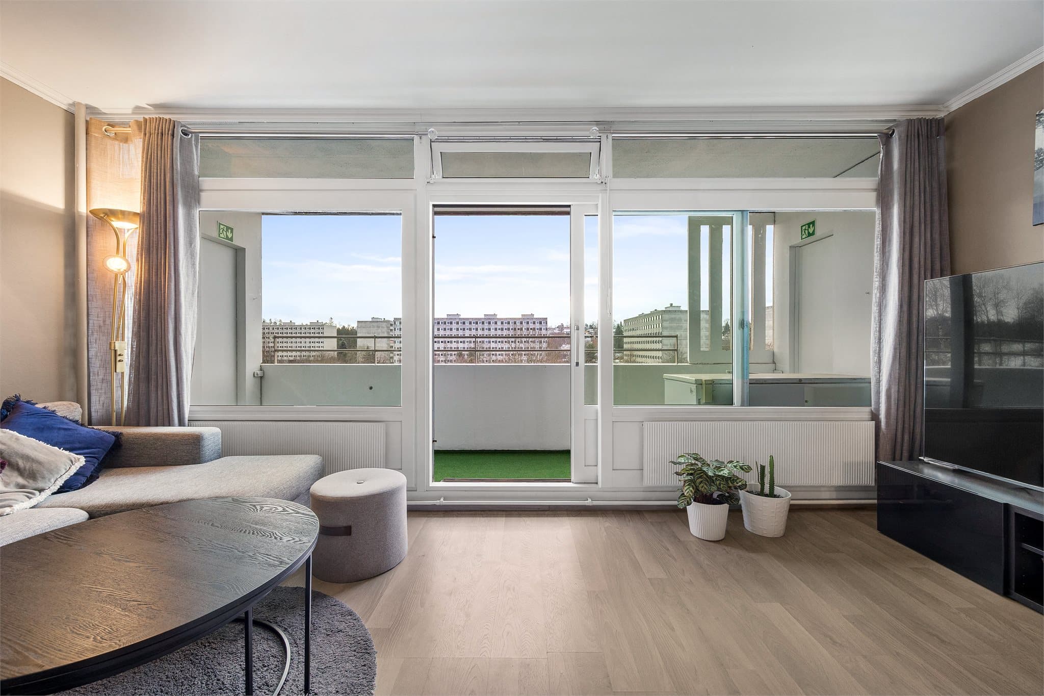 En praktisk skyvedør gir enkel adkomst til balkongen og gjør uteplassen til en naturlig forlengelse av stuen.