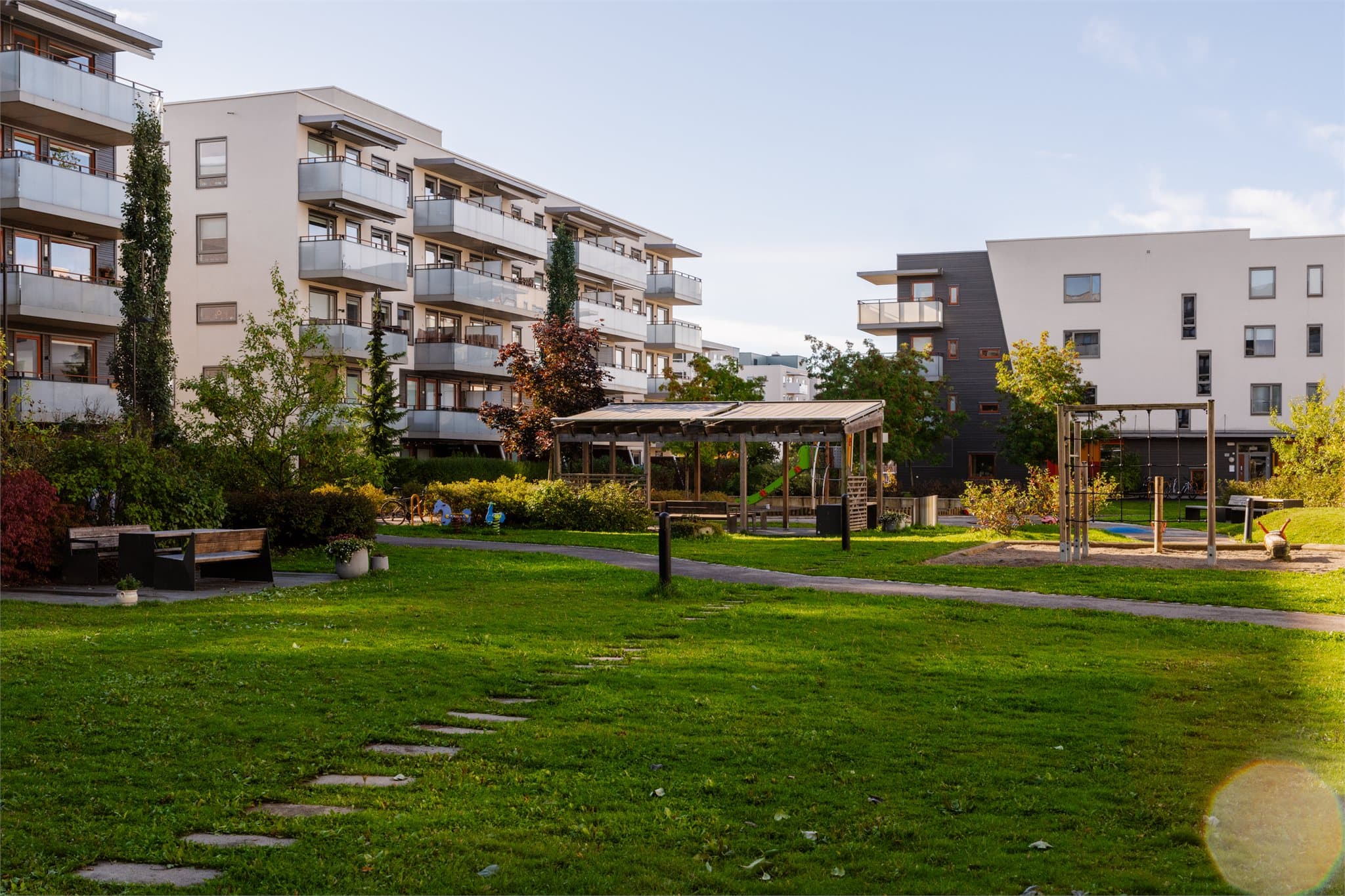 Skjermede fellesarealer med plen og gangveier mellom byggene.