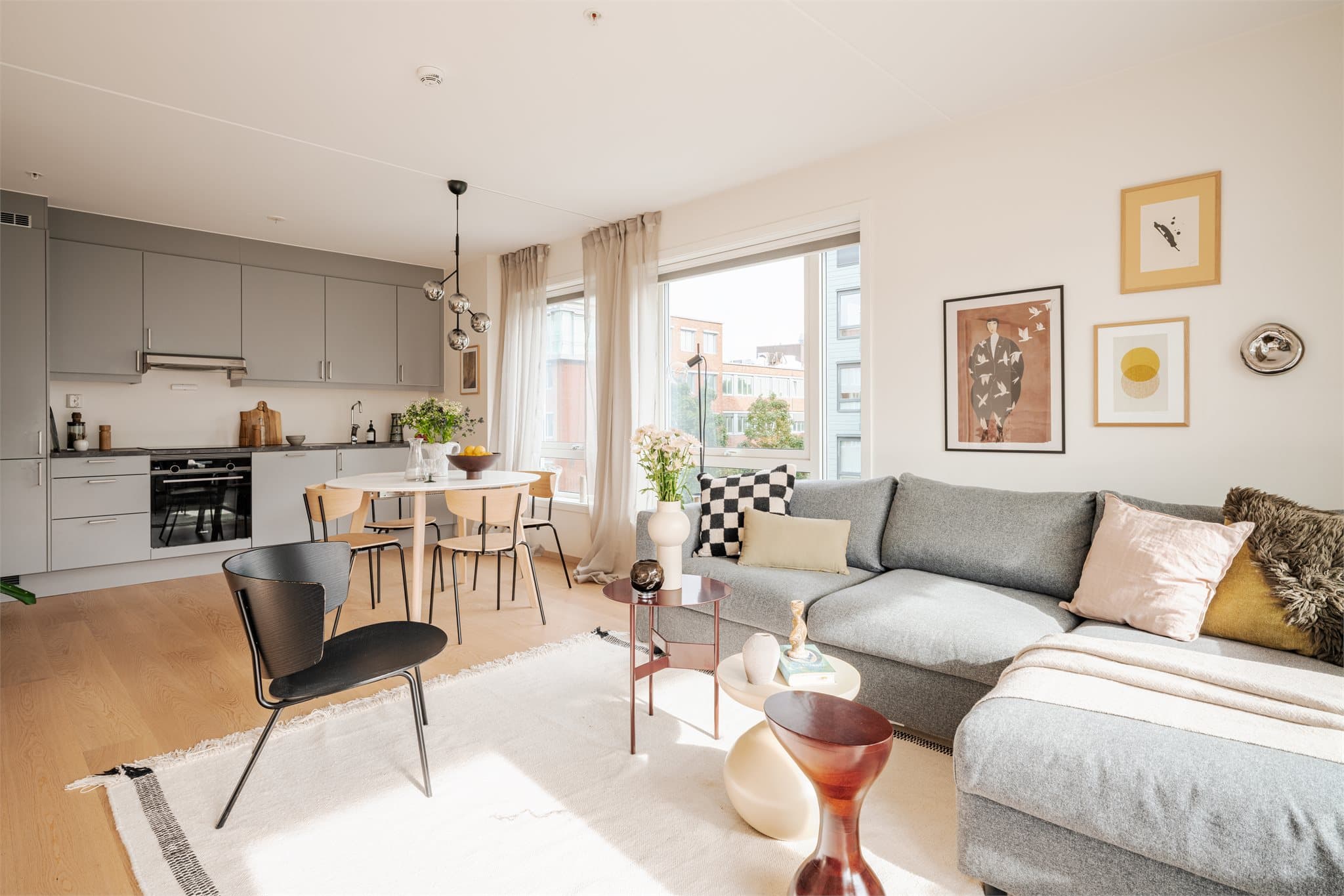 Romslig stue med åpen planløsning mot kjøkken og spiseområde.