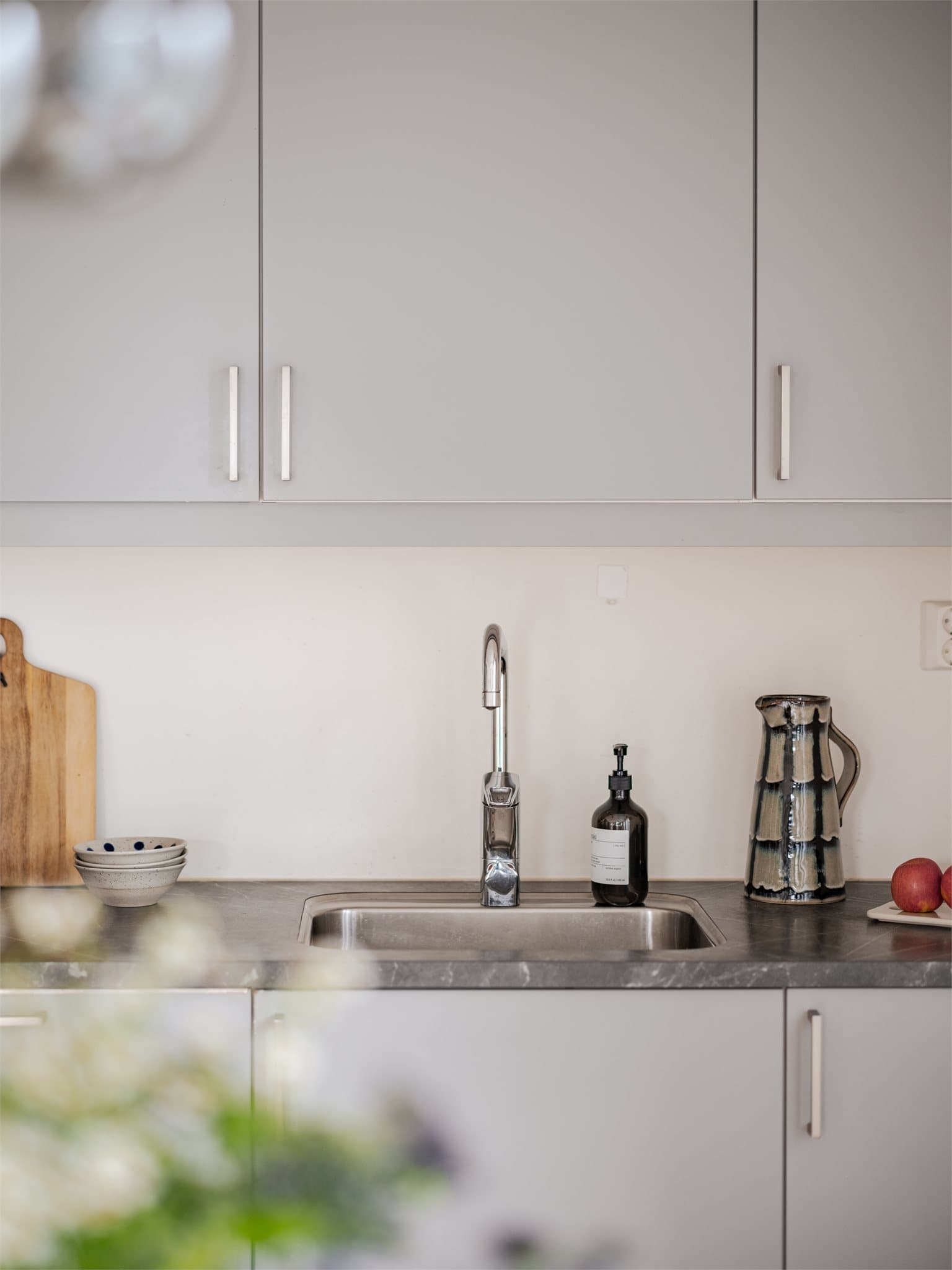 Kjøkkeninnredning med glatte, fabrikklakkerte fronter og laminatbenk med underlimt stålkum.