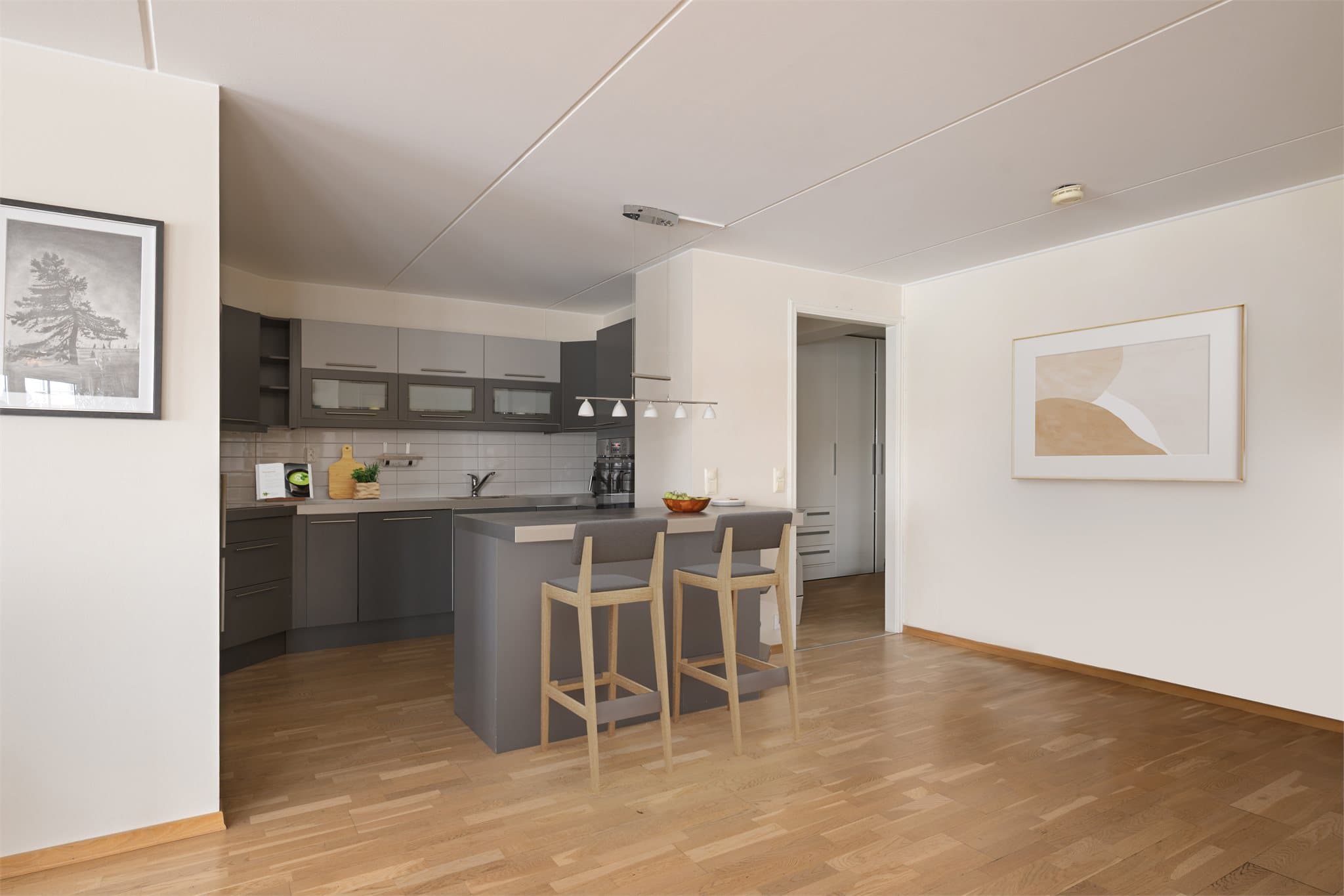 Lys og trivelig åpen stue/kjøkkenløsning med gode arbeidsflater og kjøkkenøy med sitteplasser. Gjennomgående 3-stavs eikeparkett gir et helhetlig og tidløst uttrykk. (Digitalt møblert bilde)