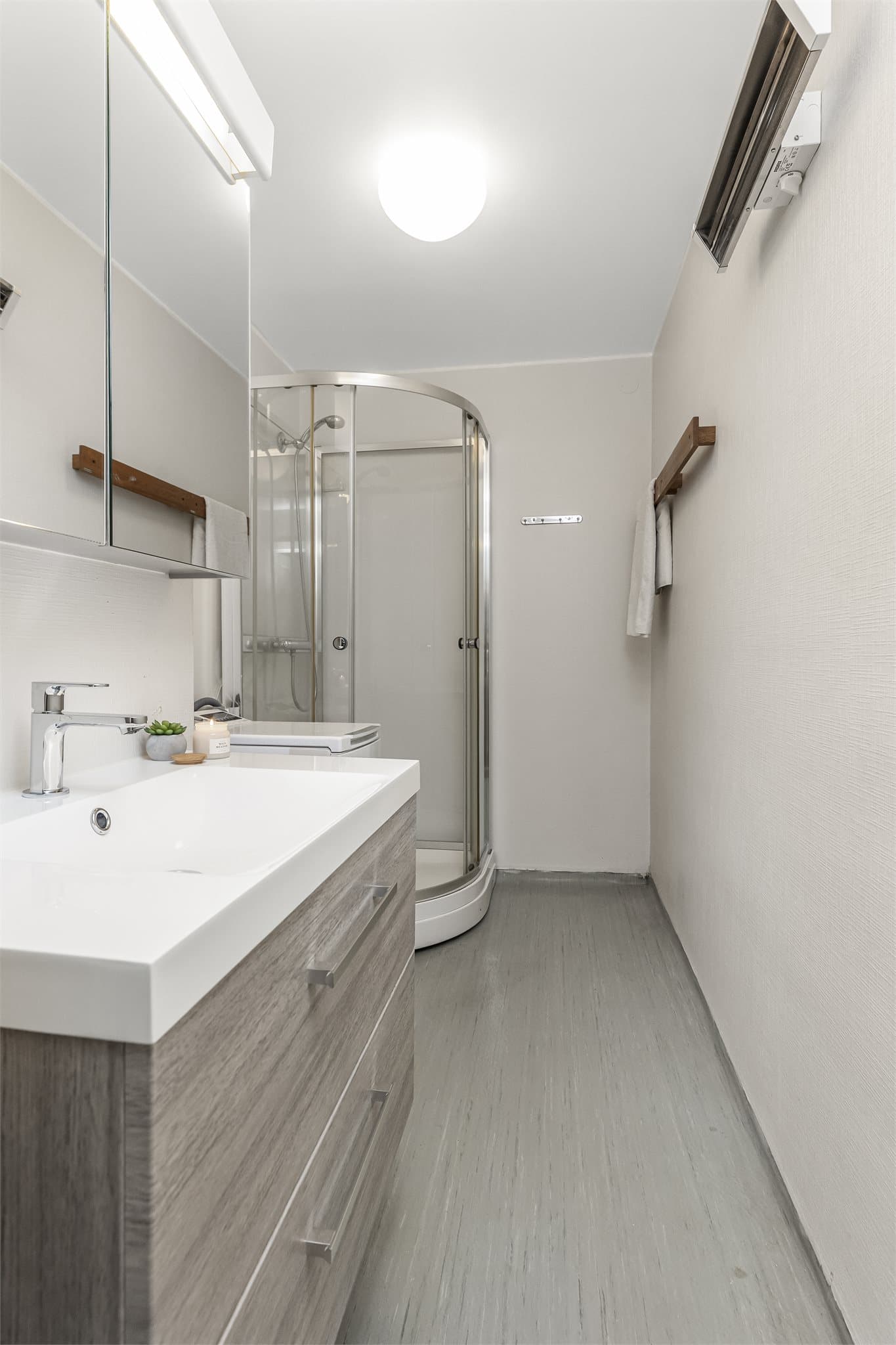 Badet er av eldre dato, men har fått flere oppgraderinger de siste årene. Baderominnredning ble fornyet 2025 med moderne servantskap med skuffer og heldekkende servant. Over innredning er det speilskap for oppbevaring.