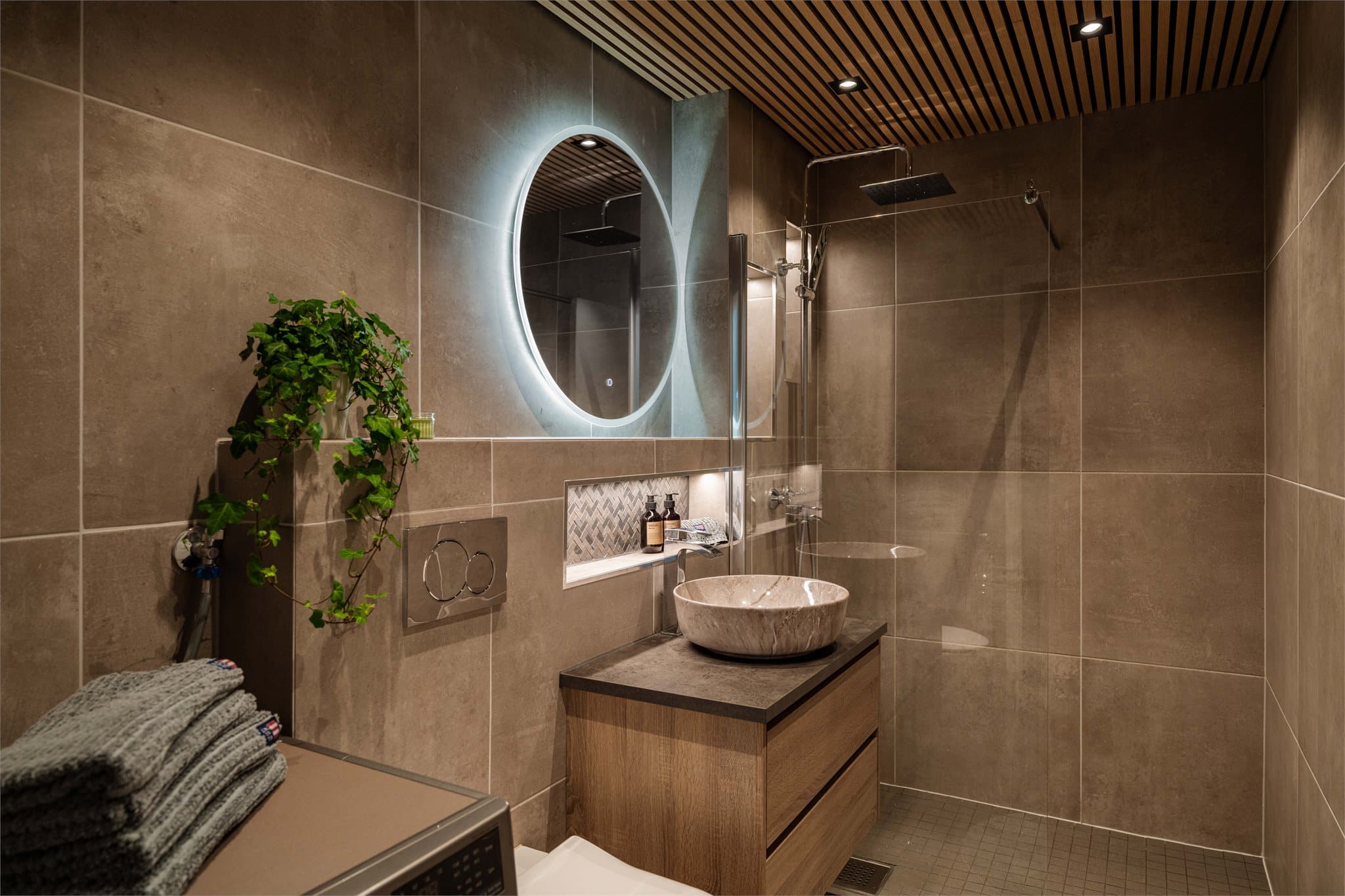 Badet ble pusset opp i 2023 med fliser og varmekabler i gulvet. I taket er det lekre spiler med downlights.