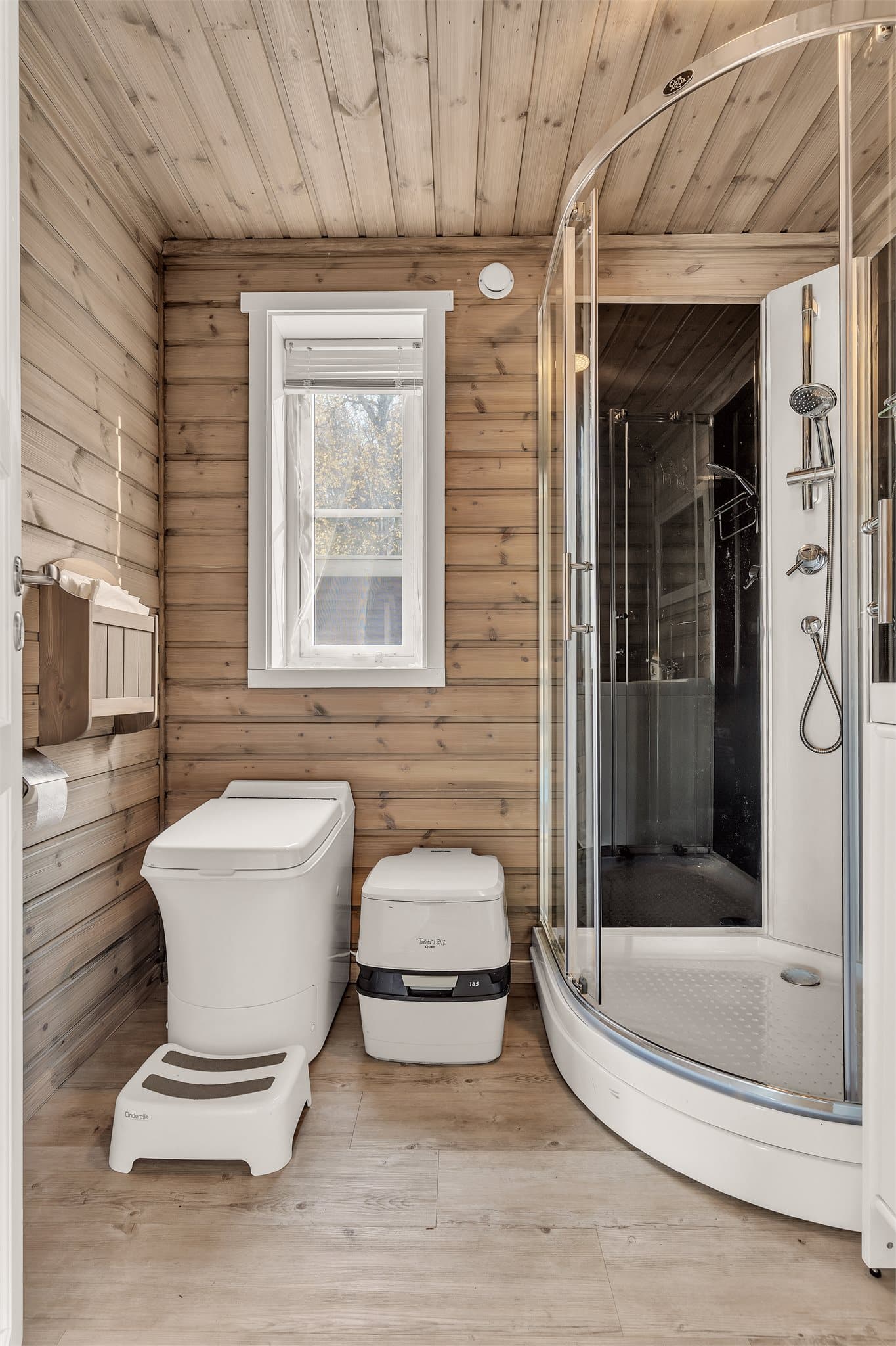 Badet har klikkvinyl på gulvet, beisede panelvegger og dusjkabinett.