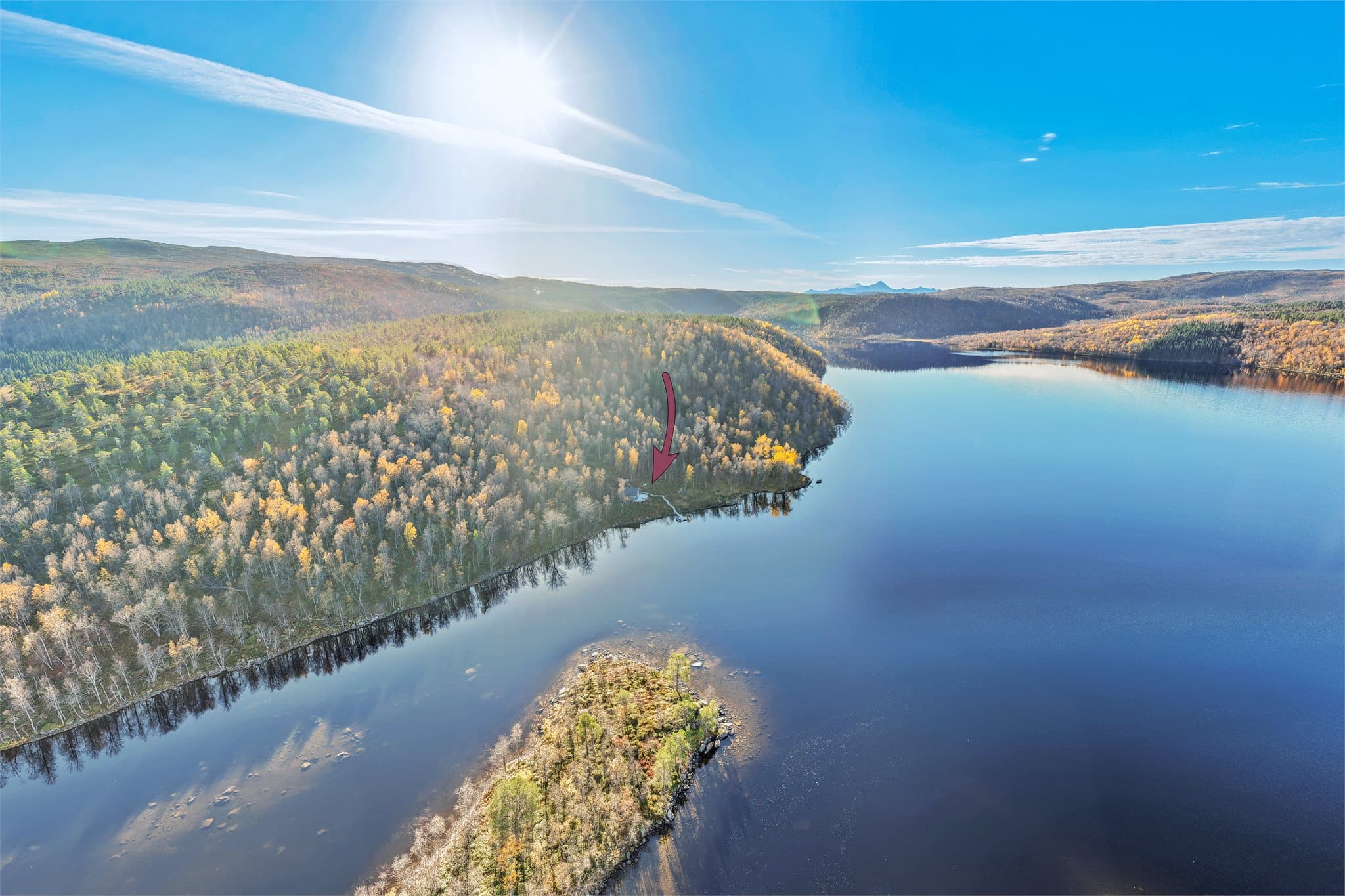Kilvatnet strekker seg gjennom landskapet med hytten omkranset av skogkledde åser.