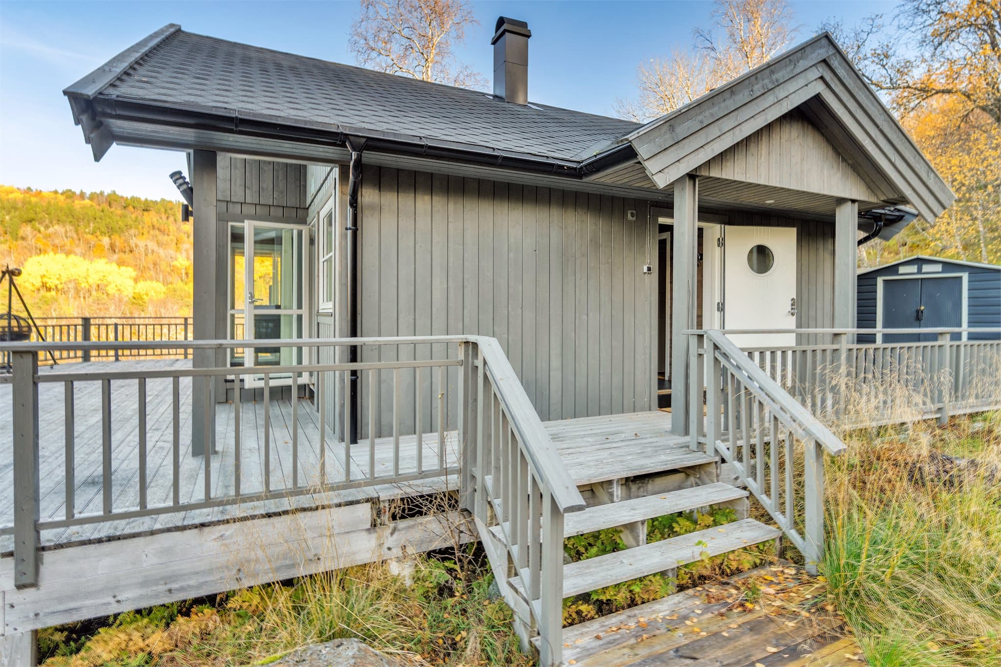 Overbygd inngangsparti med trapp i trykkimpregnert trevirke.