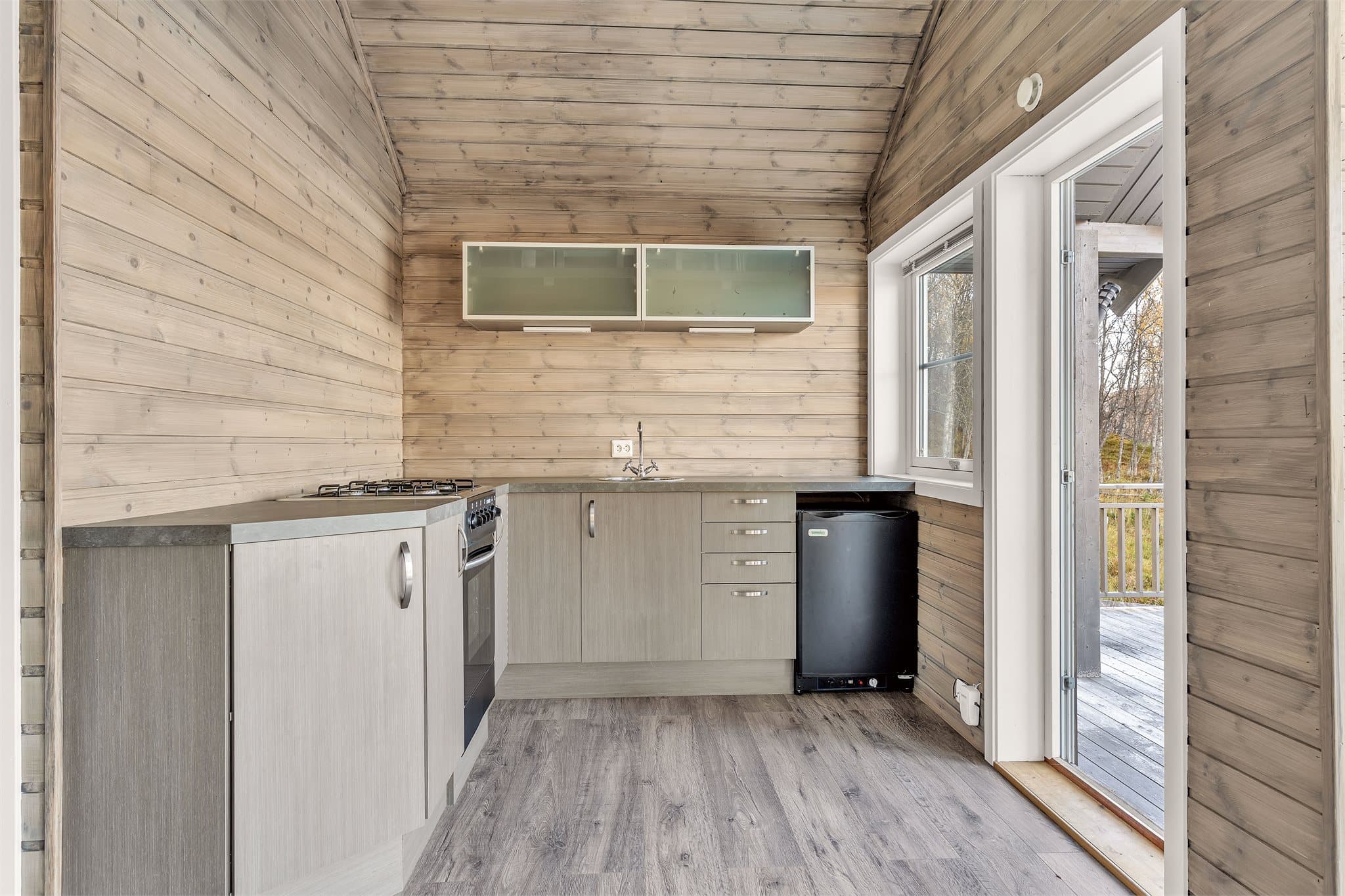 Kjøkkenet ligger i åpen løsning mot stuen med glassdør ut til verandaen.