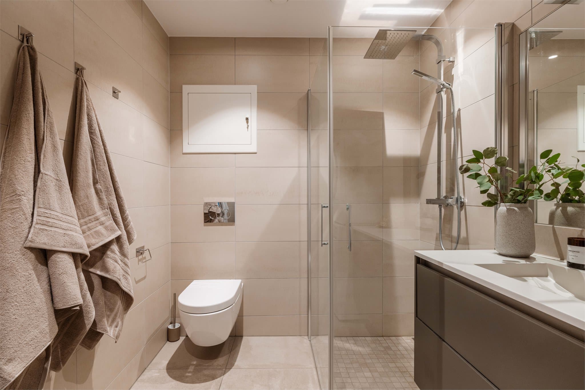 Leiligheten har et flislagt bad ved entréen, oppført i byggeåret. Badet har en praktisk og moderne innredning med servantskap med glatte, fabrikklakkerte fronter og heldekkende servant.