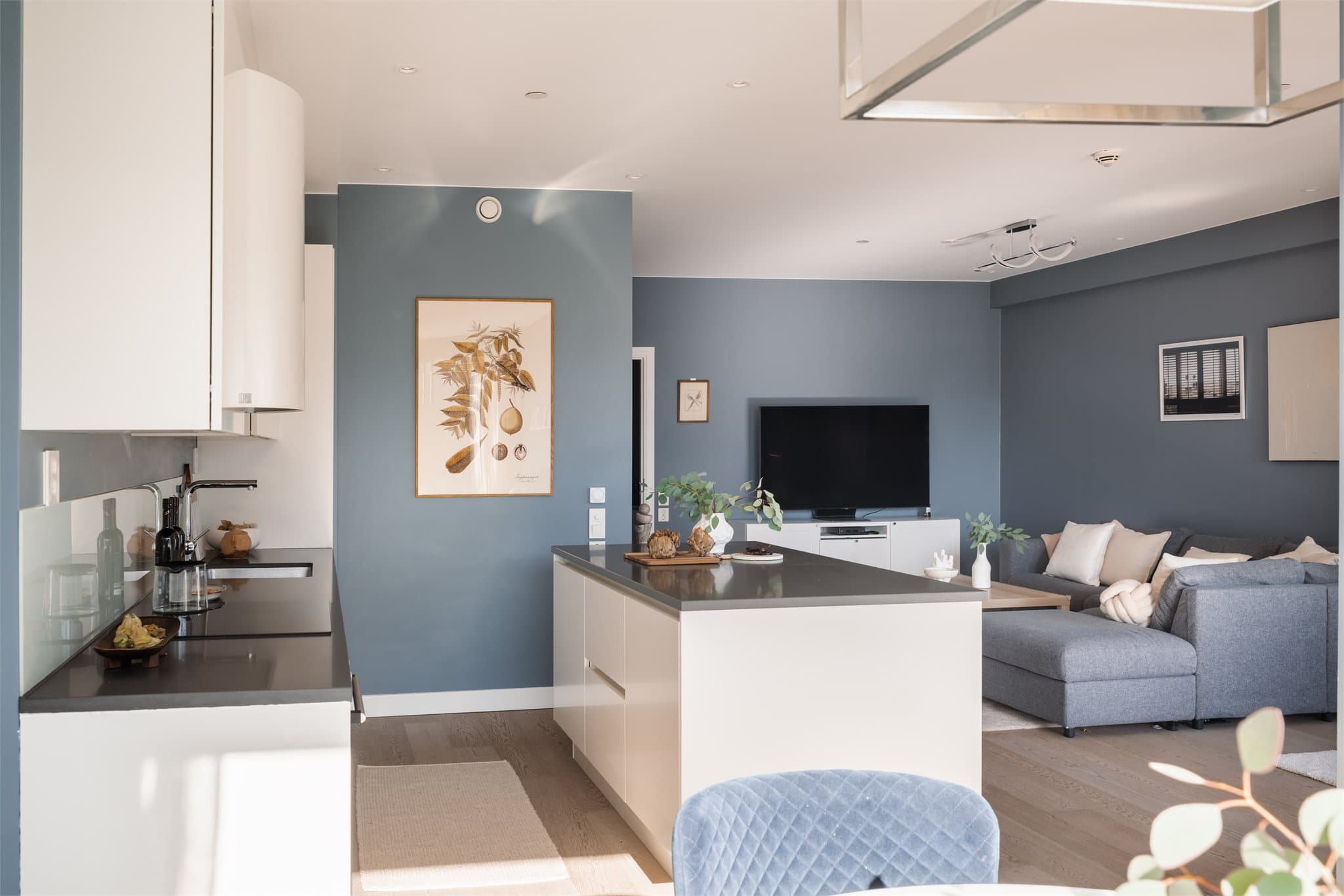 Over benkeplaten er det montert stilrene glassplater som både beskytter veggene og gir et moderne uttrykk. Arbeidsbelysning er ivaretatt med LED-lyslist under overskap, noe som gir gode lysforhold på kjøkkenbenken.