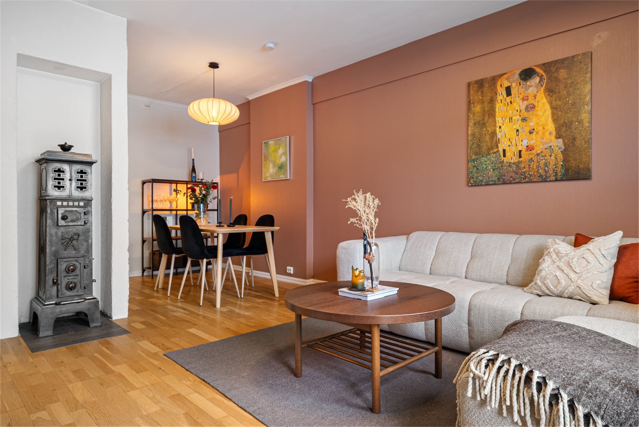 Stuen rommer fint både sofagruppe og spisebord, med vedovnen og teglsteinspipen som et lunt midtpunkt.