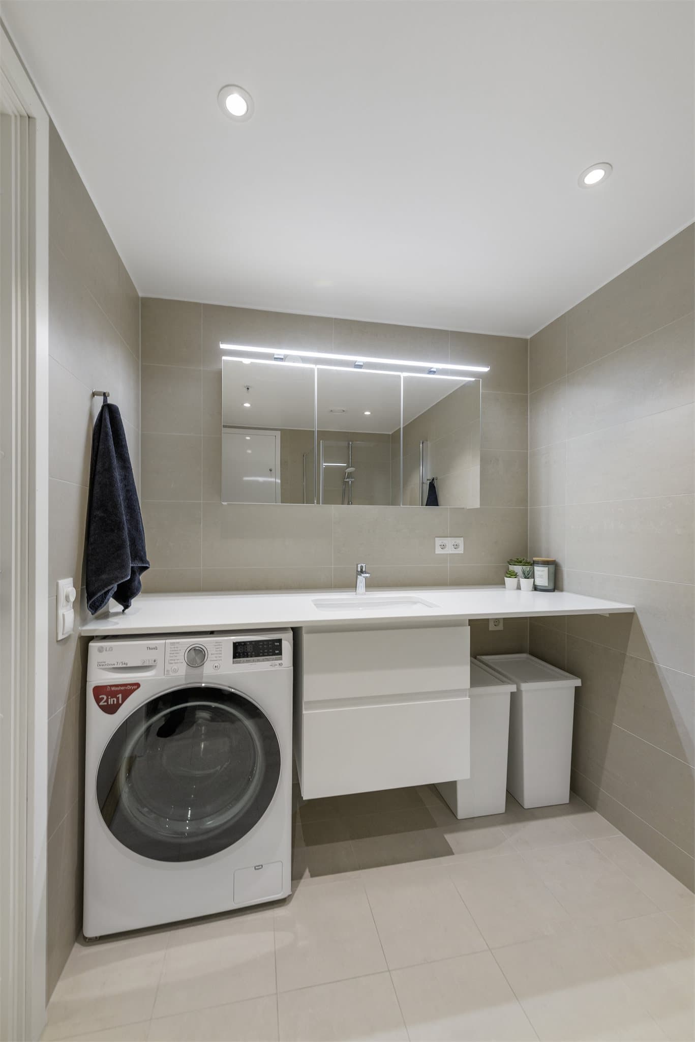 Bad med stor innredning og benkeplass over vaskemaskin. Plass til tørketrommel på høyre side