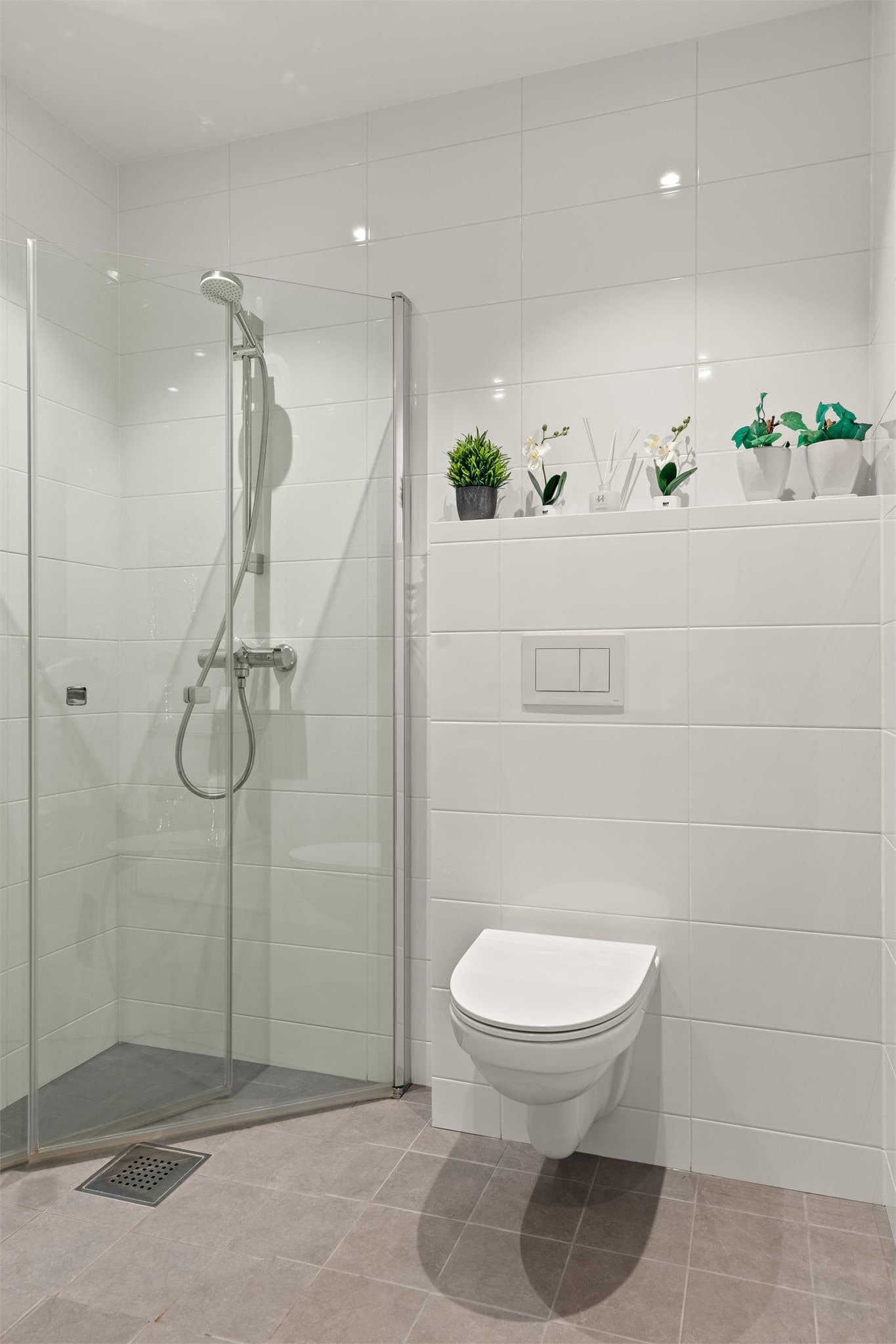 Dette badet er flislagt, har elektriske varmekabler i gulvet, veggmontert toalett og dusjvegger.