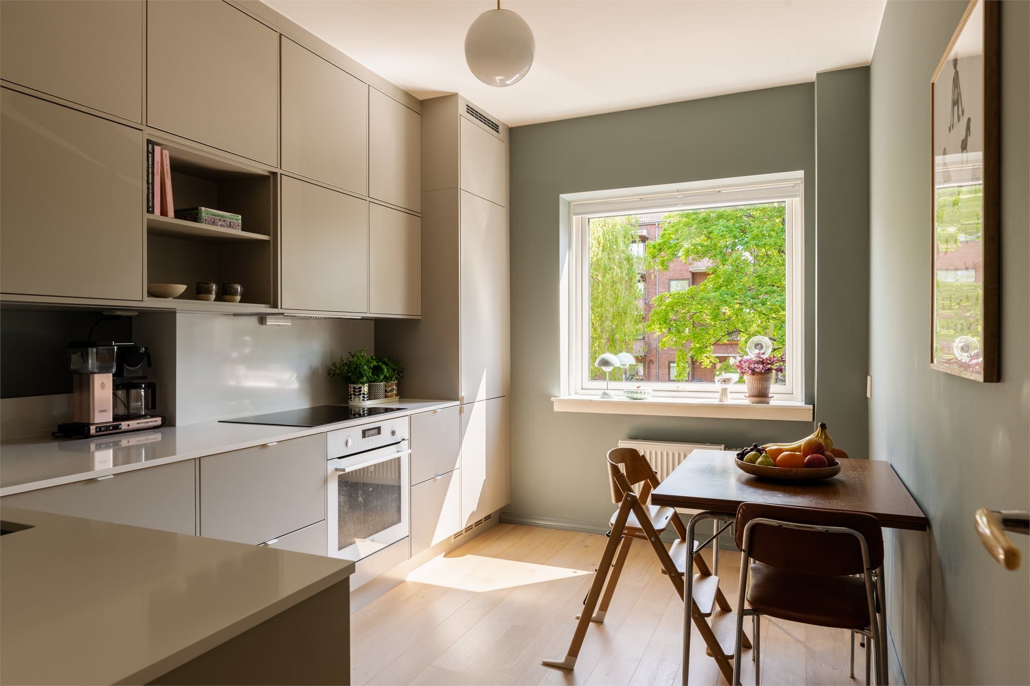 Lekker kjøkkeninnredning i delikate fargetoner, med naturlig plass til et spisebord.