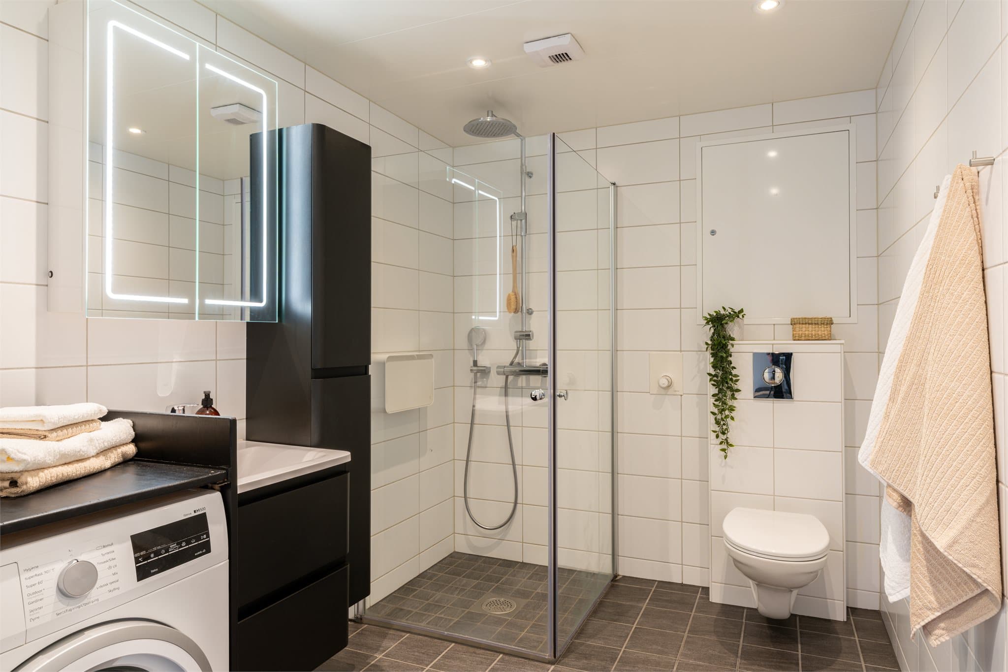 Flislagt bad med gulvvarme og downlights i tak, noe som gir en behagelig atmosfære under morgen- og kveldstellet.