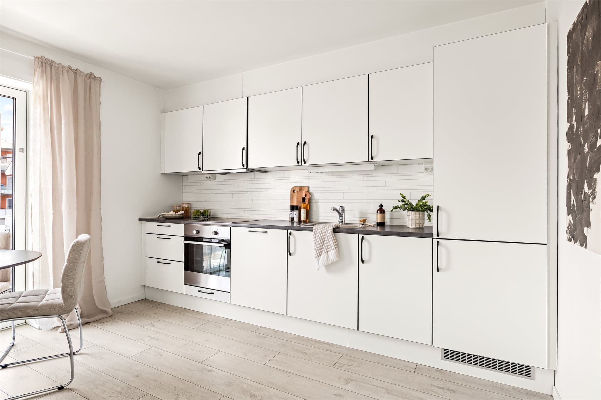 Leiligheten har et funksjonelt og lekkert kjøkken med integrerte hvitevarer og hvite, glatte fronter.