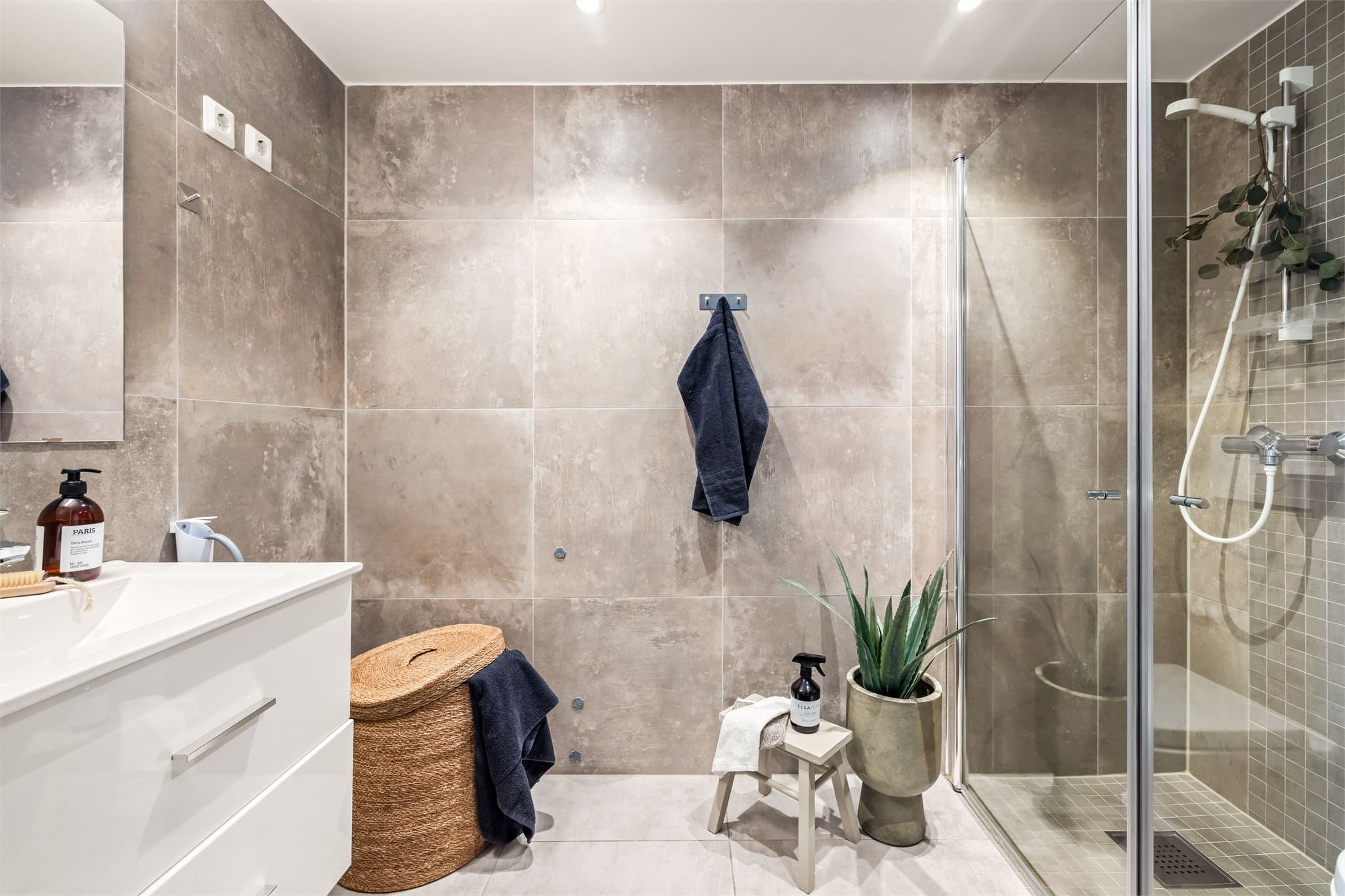 Moderne bad med mørke gulvfliser, gulvvarme og downlights i himlingen.