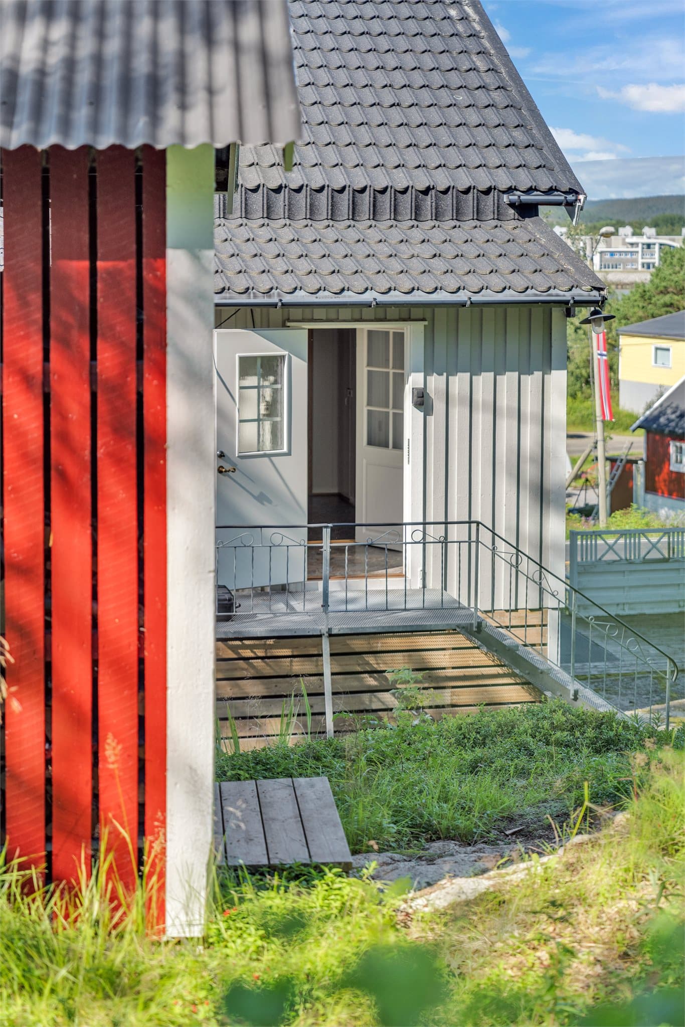 Hovedinngangen i første etasje har en hvit ytterdør med glassfelt.