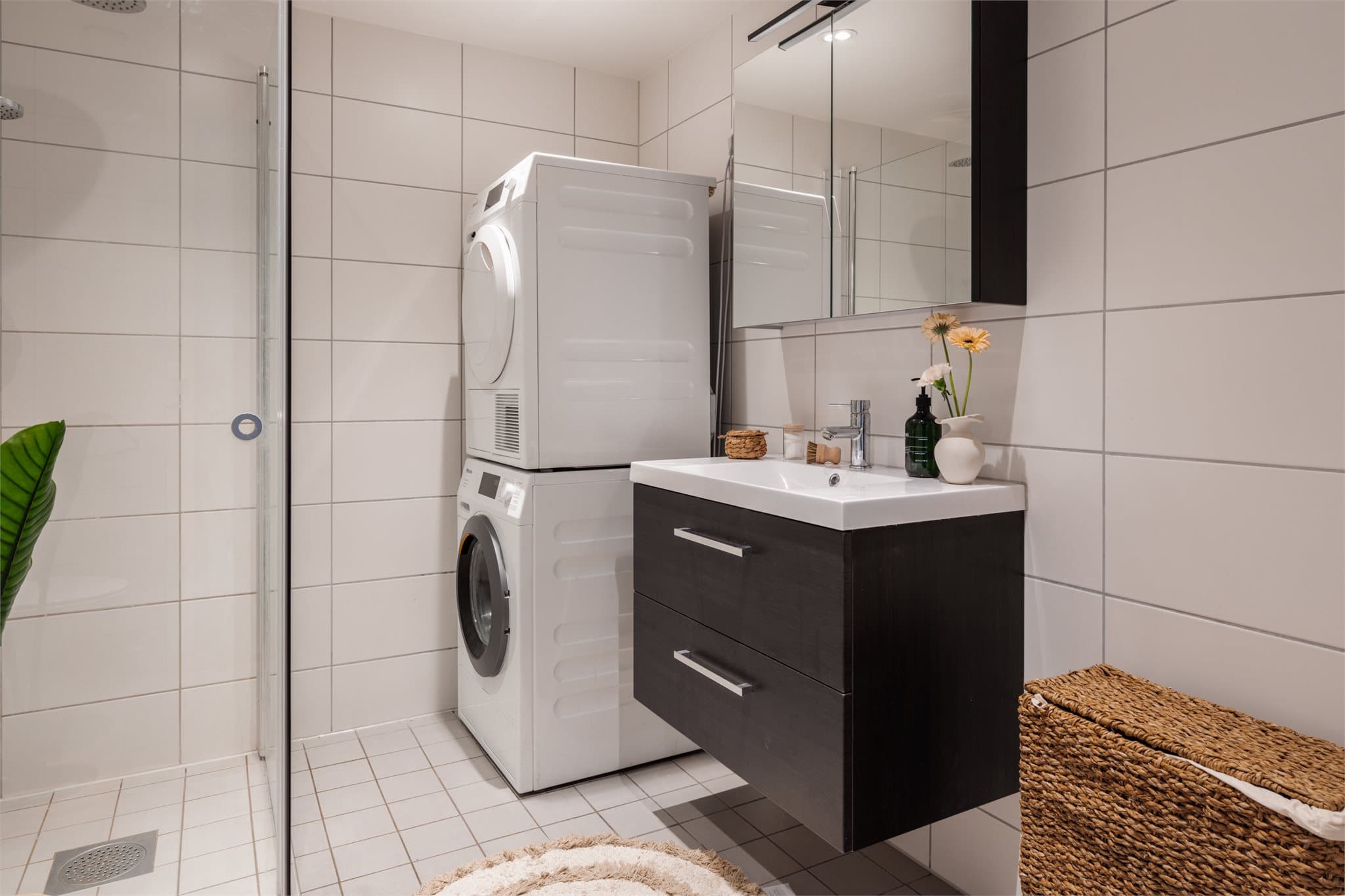 Den mørke, moderne baderomsinnredningen skaper en fin kontrast mot de lyse flisene.