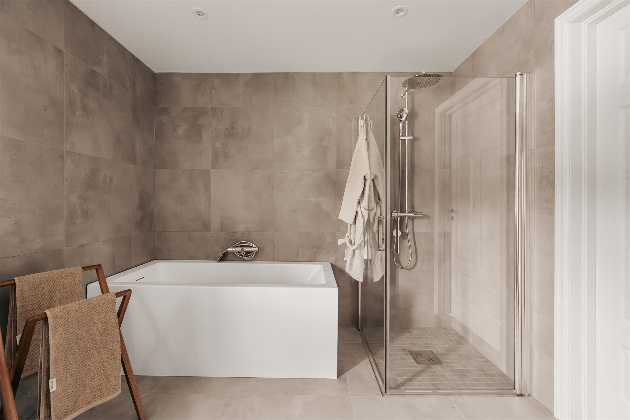 Innredningen består av servant, veggfestet klosett, badekar og dusjhjørne.