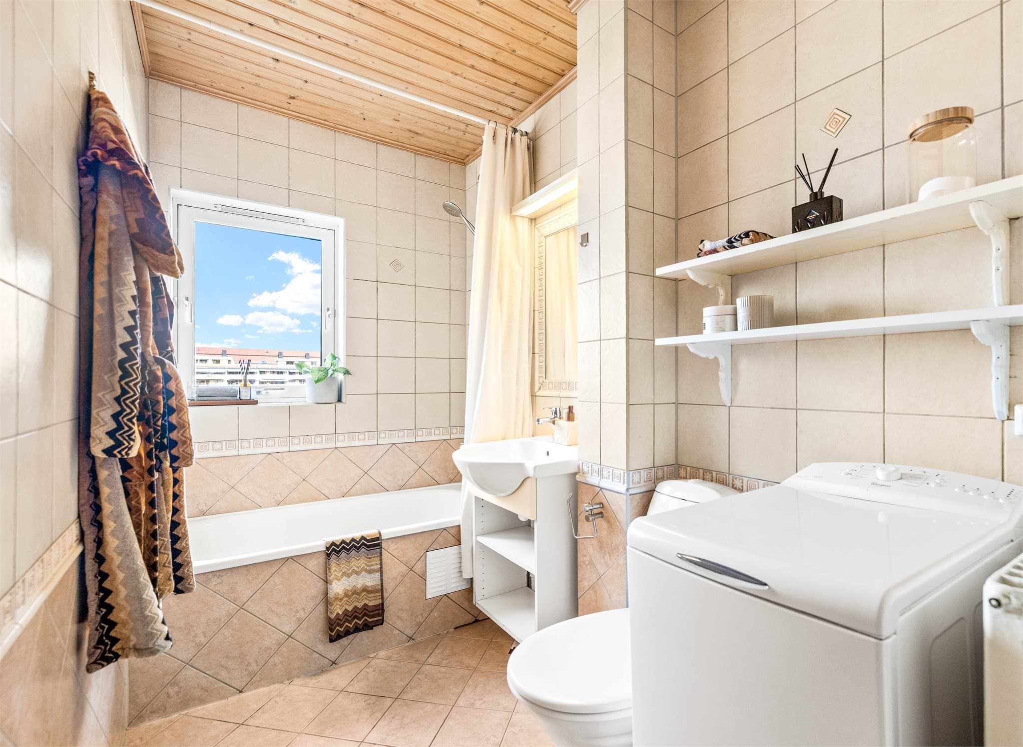 Badet er flislagt og utstyrt med badekar, samt opplegg for vaskemaskin.