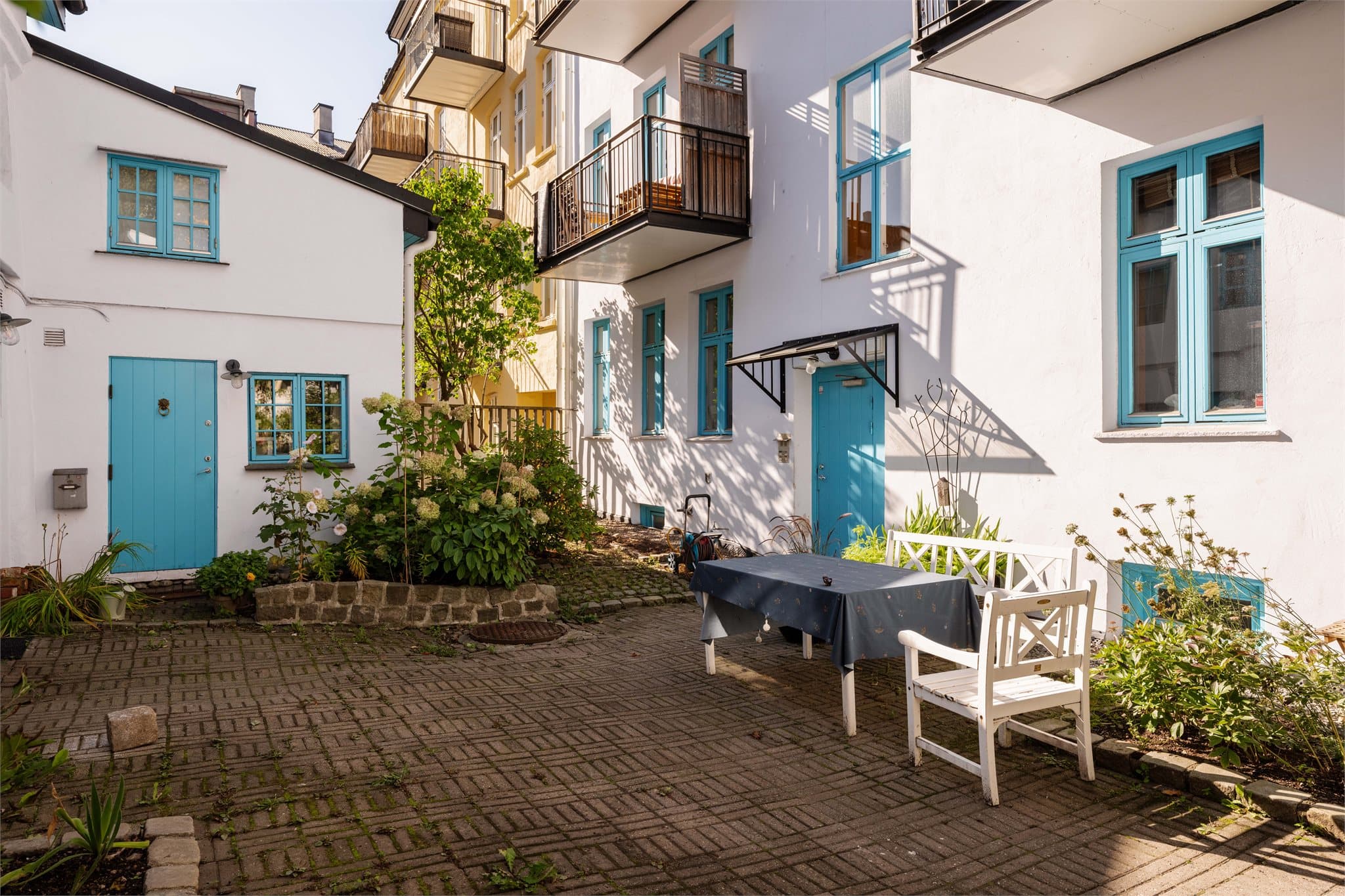 En hyggelig oase midt i byen – en frodig felles bakgård med grønne planter og deilig sydlandsk stemning.