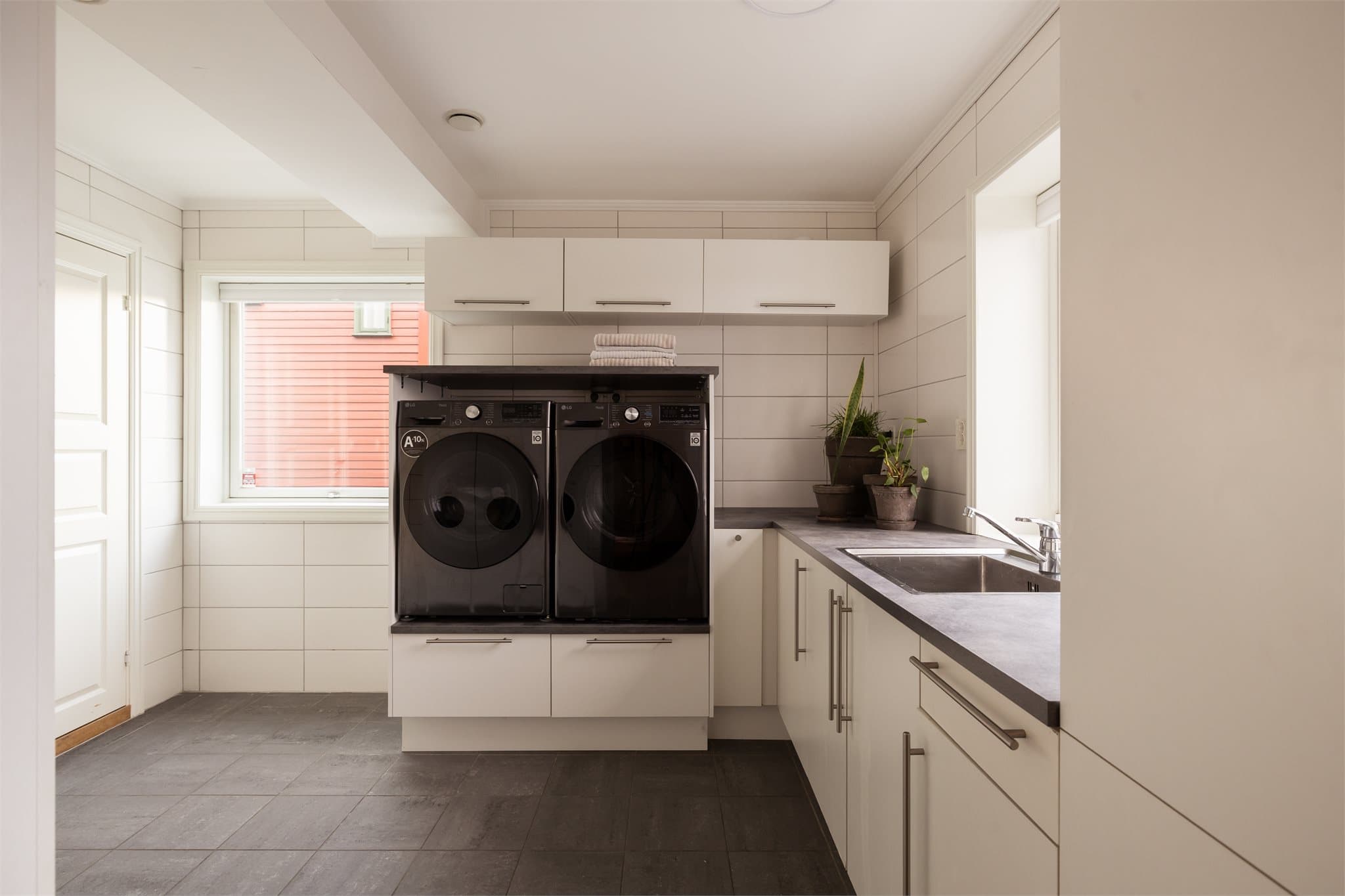 Med direkte adkomst fra entréen får du et praktisk vaskerom, ideelt når familien kommer inn med skitne sko eller våte poter. Rommet er utstyrt med benkeskap, høyskap med glatte fronter, laminert benkeplate og nedfelt stålkum.