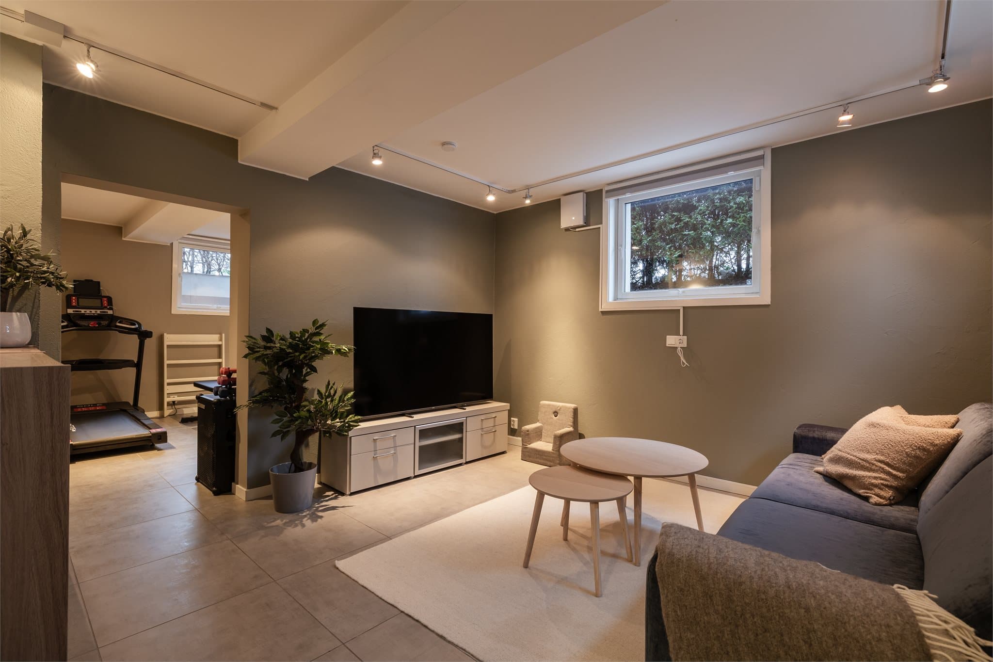 Stuen i hybelen er lys og praktisk med en åpen løsning mot kjøkkenet, noe som gir en god romfølelse og en naturlig flyt mellom sonene.