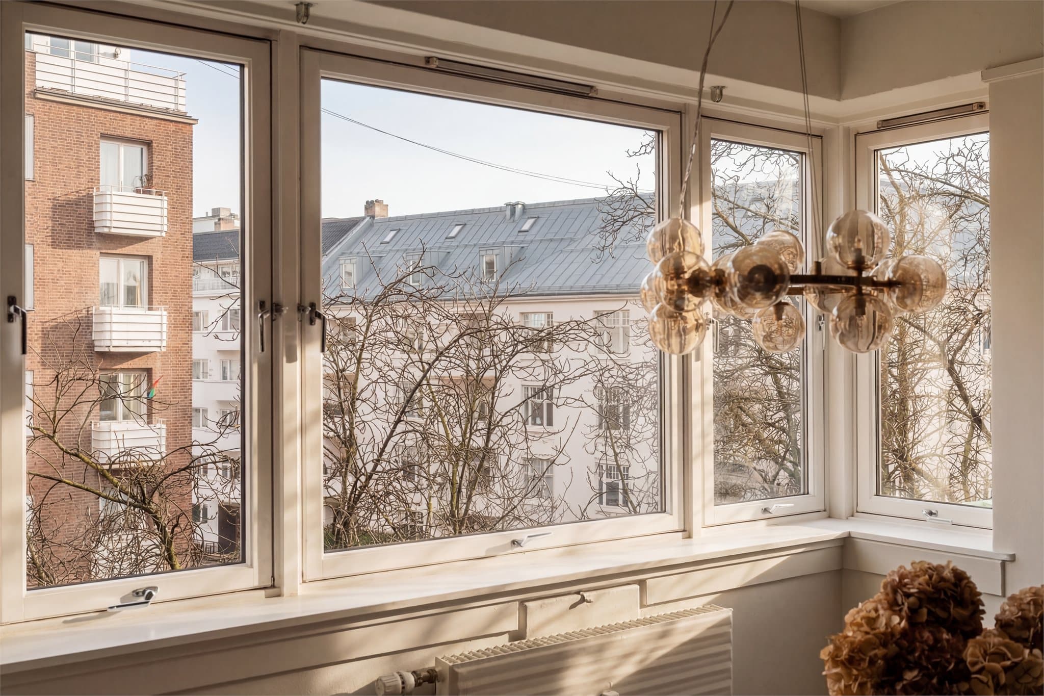 Store vindusflater med isolerglass fra 1989 som slipper inn rikelig med naturlig dagslys. Bildet er redigert med AI for å illustrere lysinnslippene på solskinnsdager.