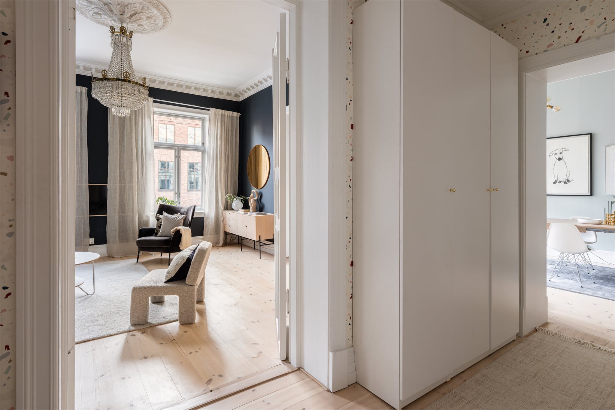 Leiligheten har en lys og luftig entré med lekkert furugulv og vegger med tapet.