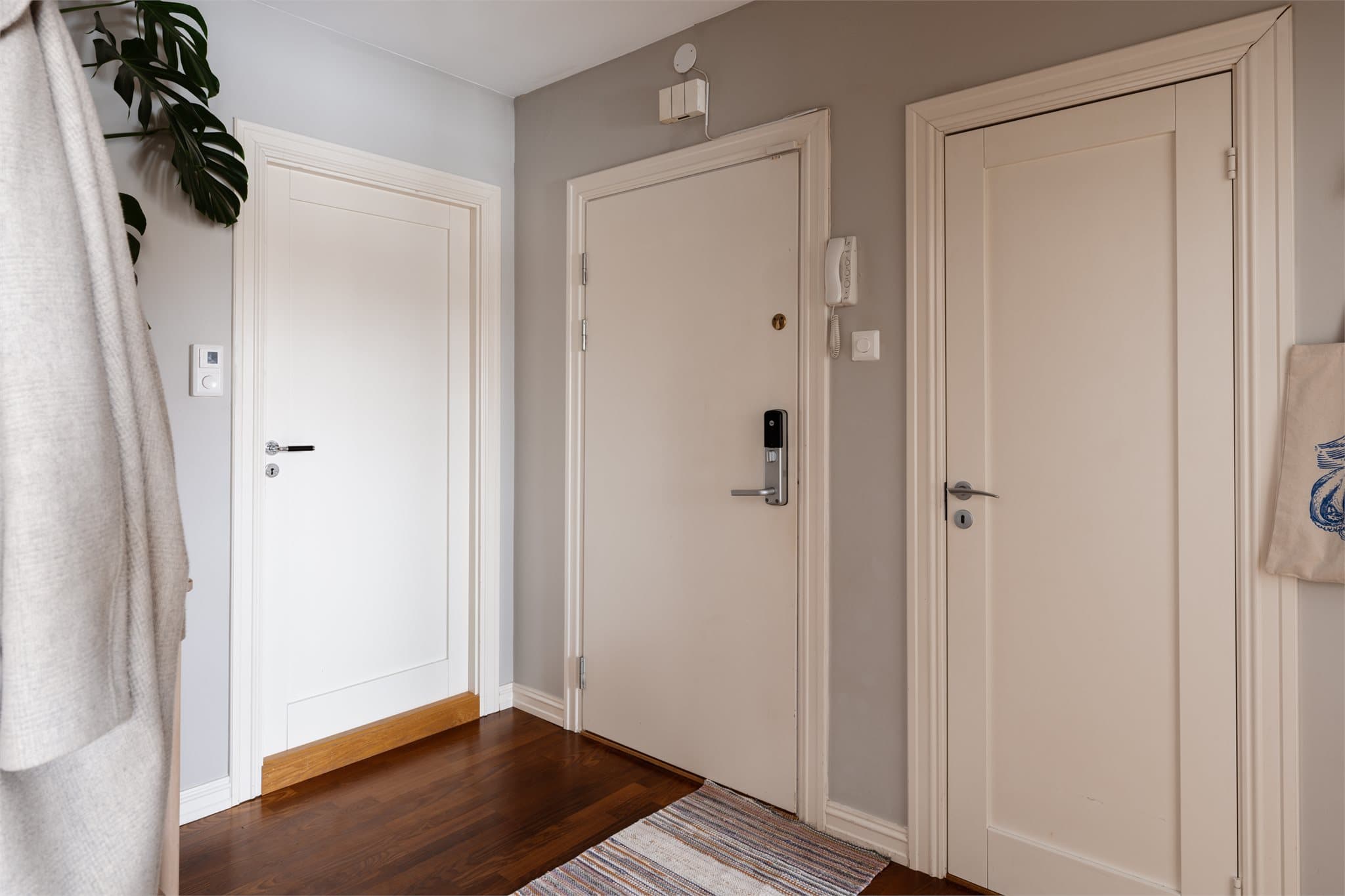 Velkommen inn i en lys entré. Inngangsdøren er utstyrt med elektronisk dørlås og porttelefon.